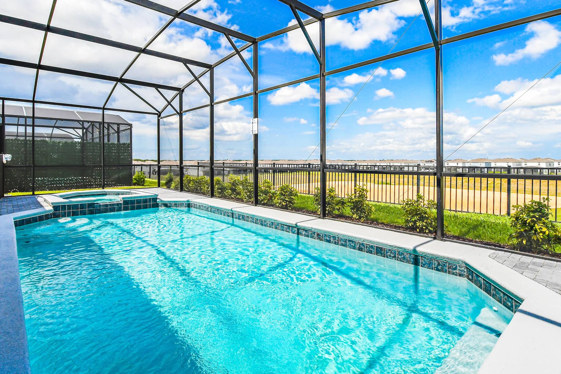 Screened-in pool and spa with open views, perfect for relaxing under the sun.