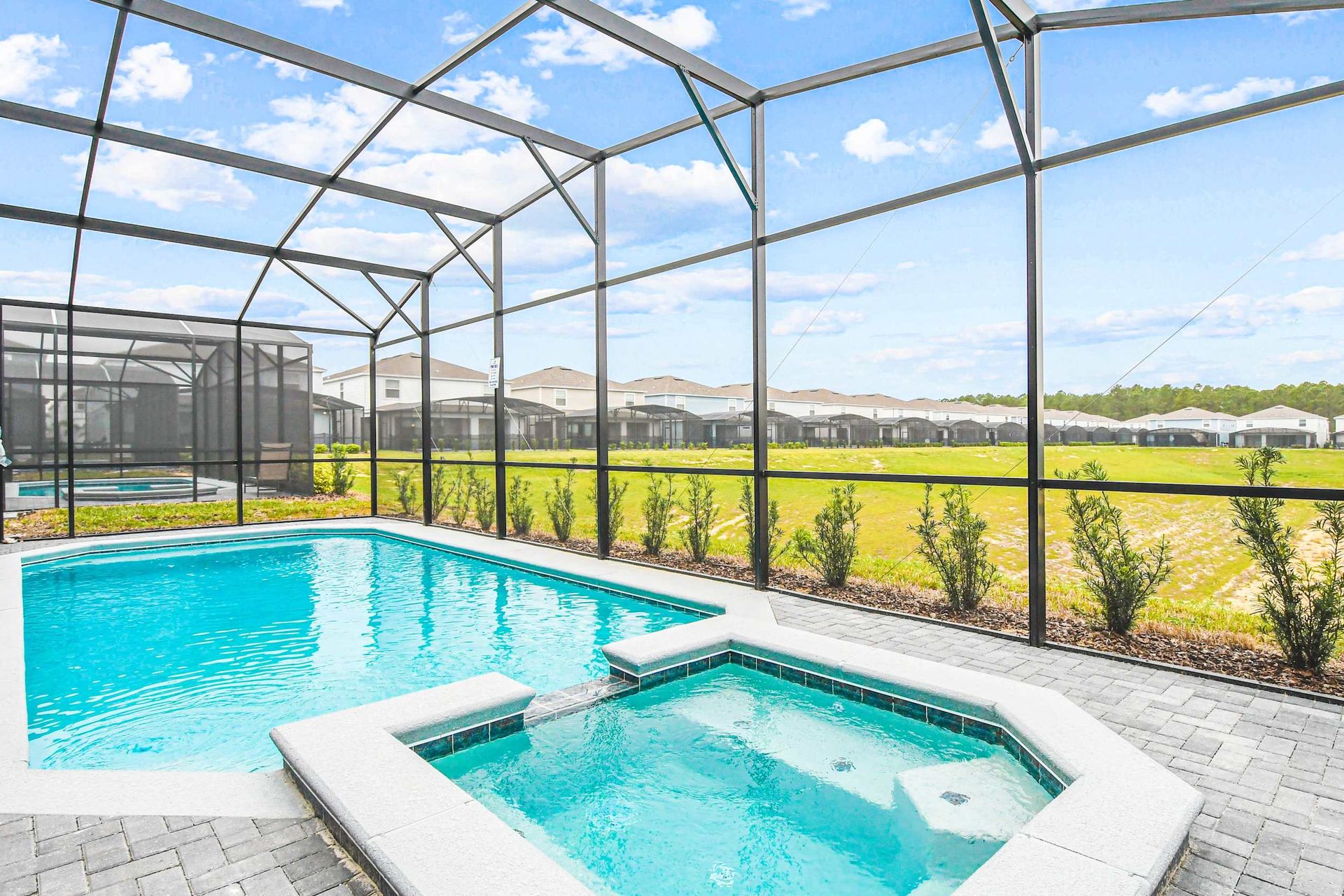 Sunny screened-in pool and spa with open views, perfect for relaxing and unwinding.