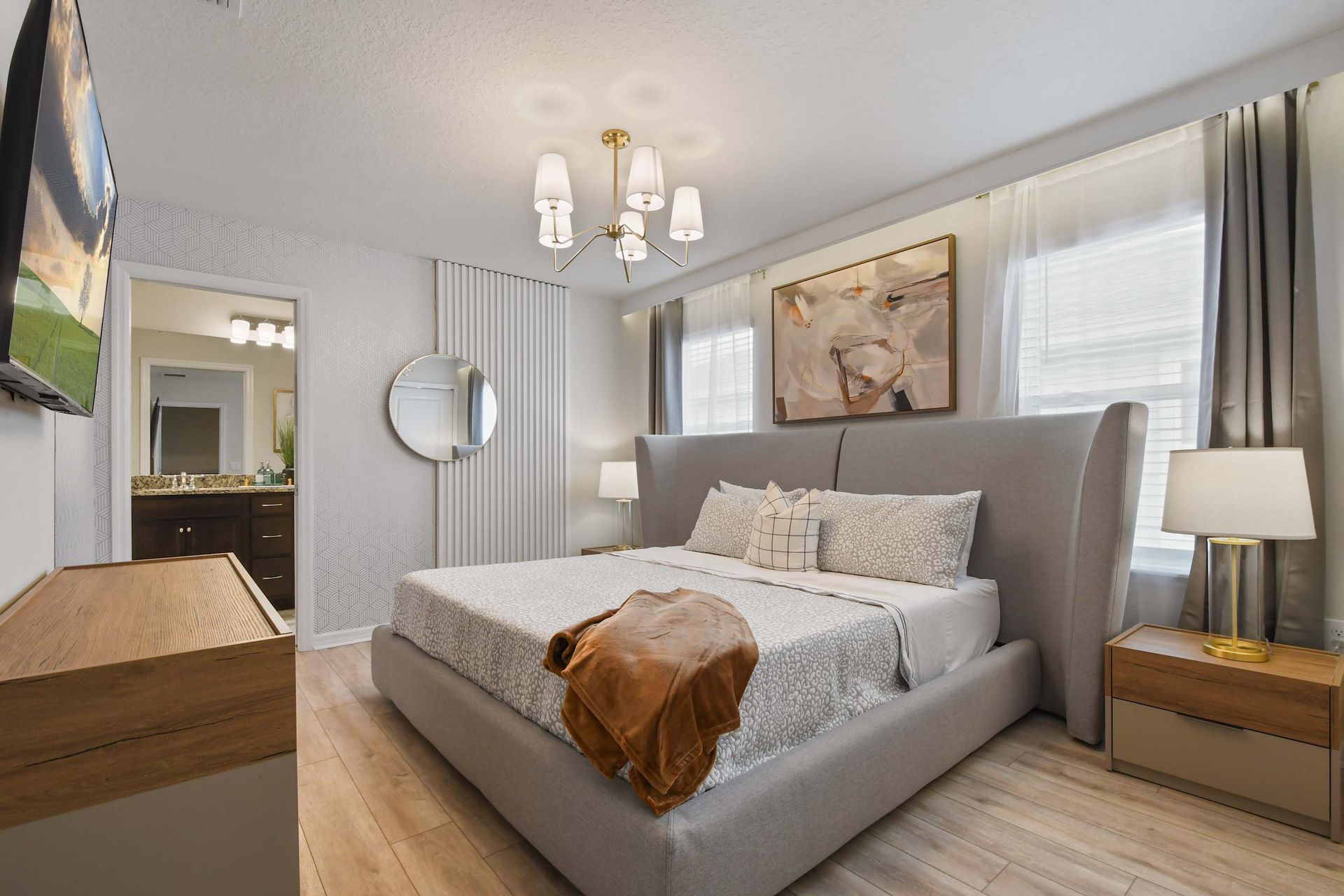Elegant bedroom with a plush king bed, modern décor, ensuite bath, and natural lighting.