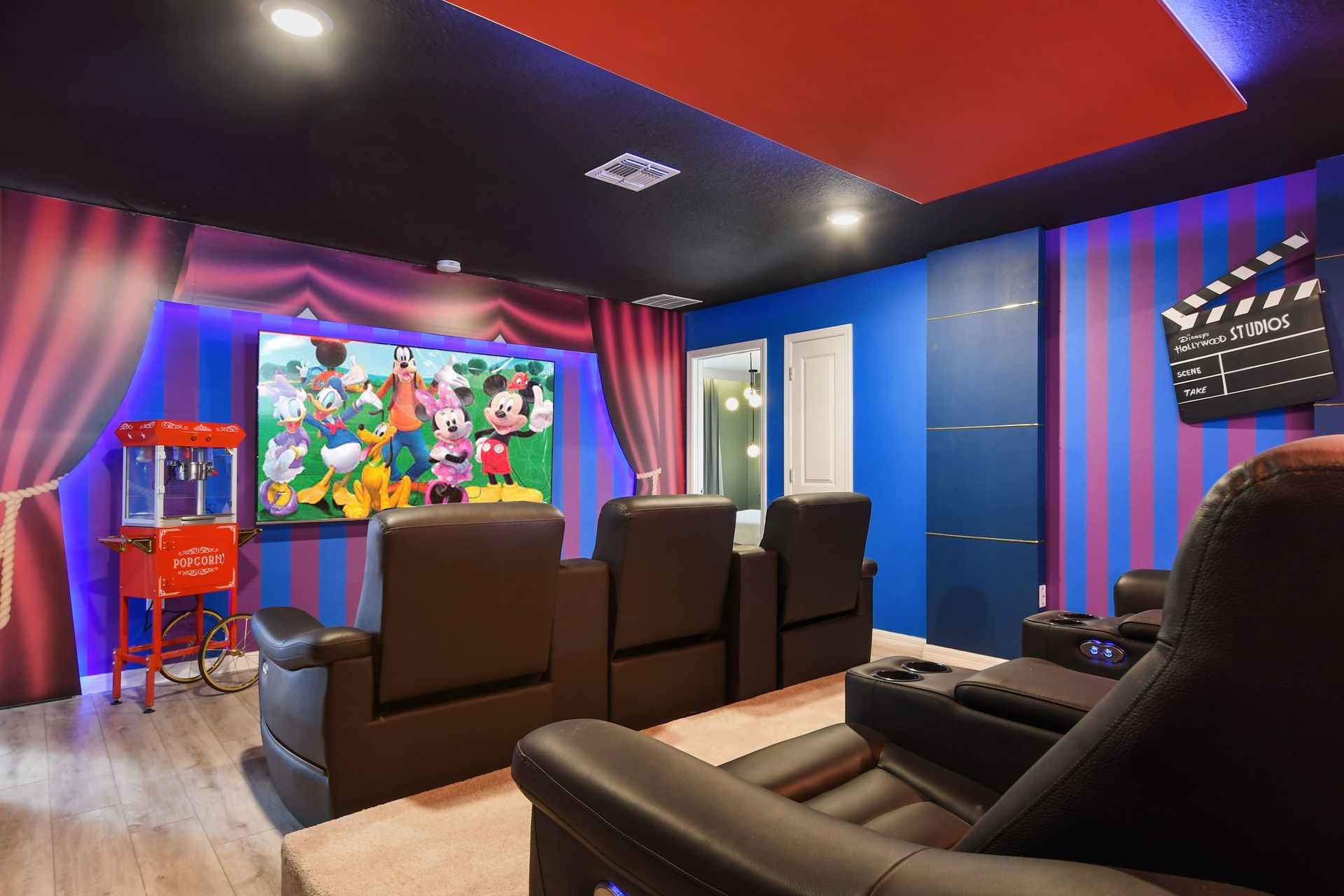 Private Disney-themed theater with recliners, surround sound, and popcorn machine.