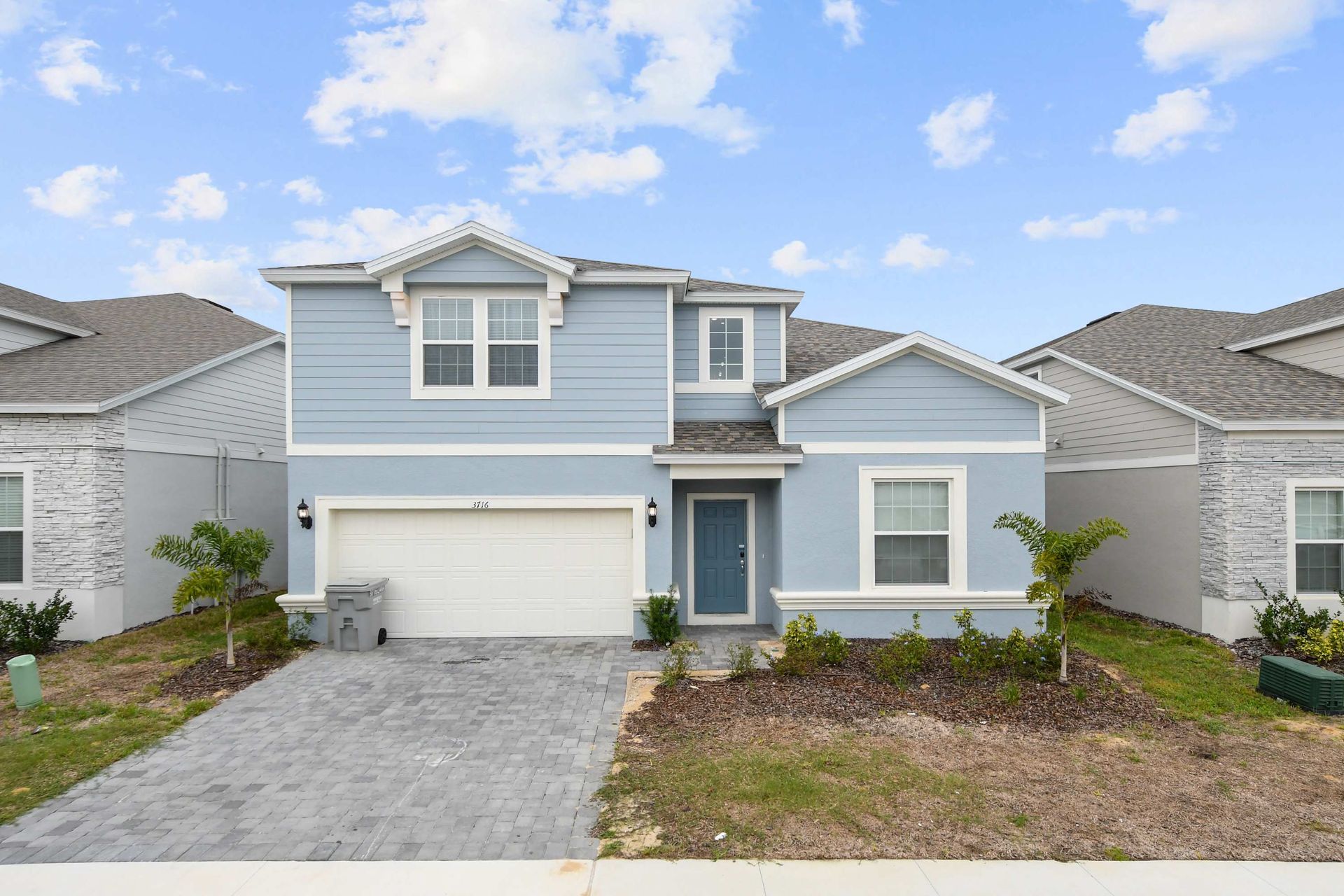Modern two-story home with a sleek blue exterior, garage, and private driveway.