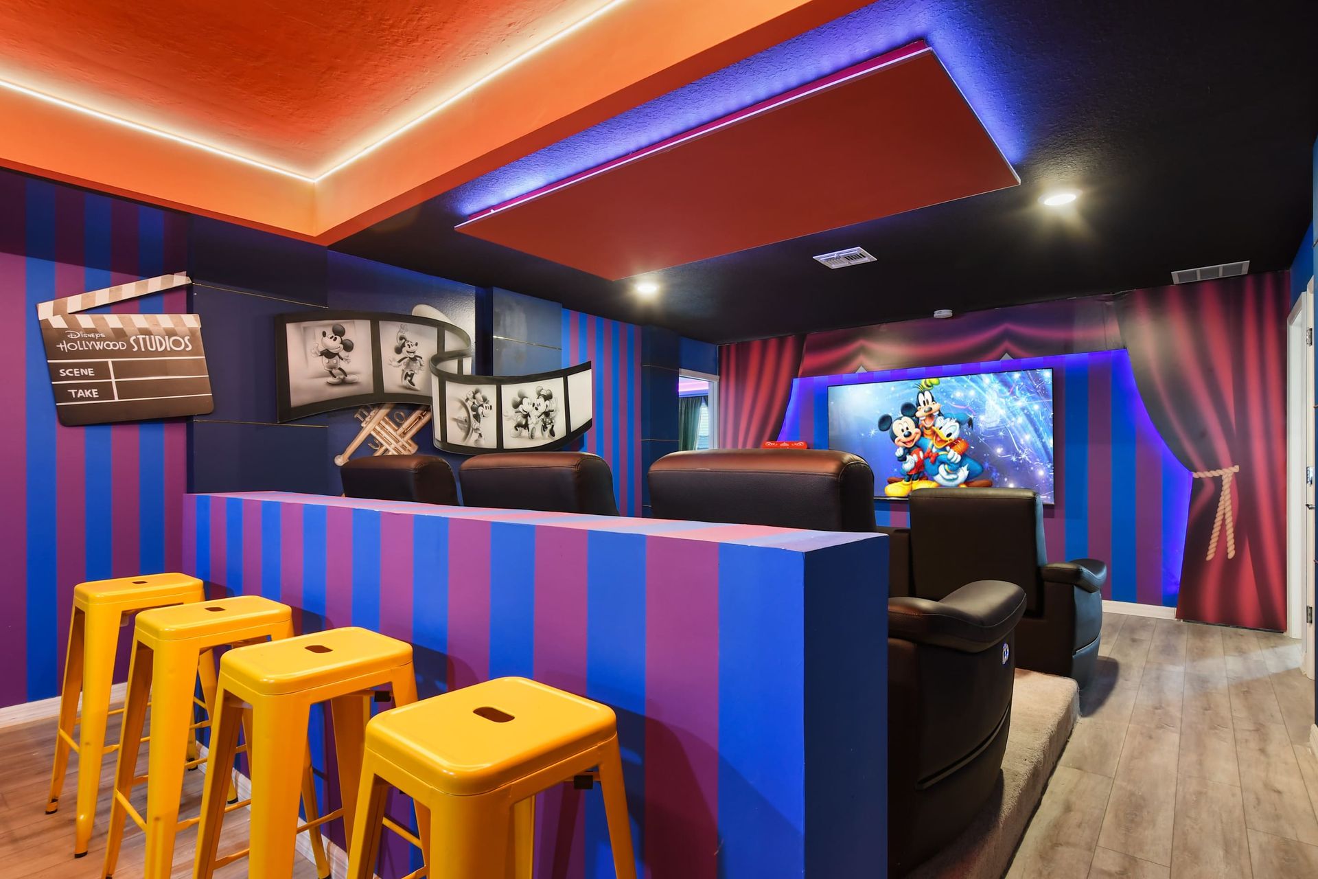 Colorful Disney-themed theater with tiered seating, bar stools, and classic cartoon charm.