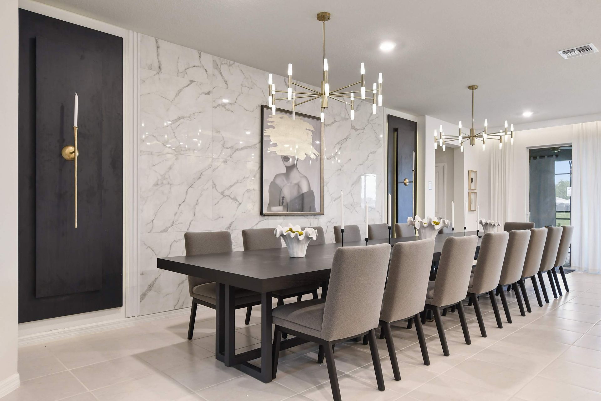 Sophisticated dining area with marble accent wall, modern chandeliers, and seating for 16.