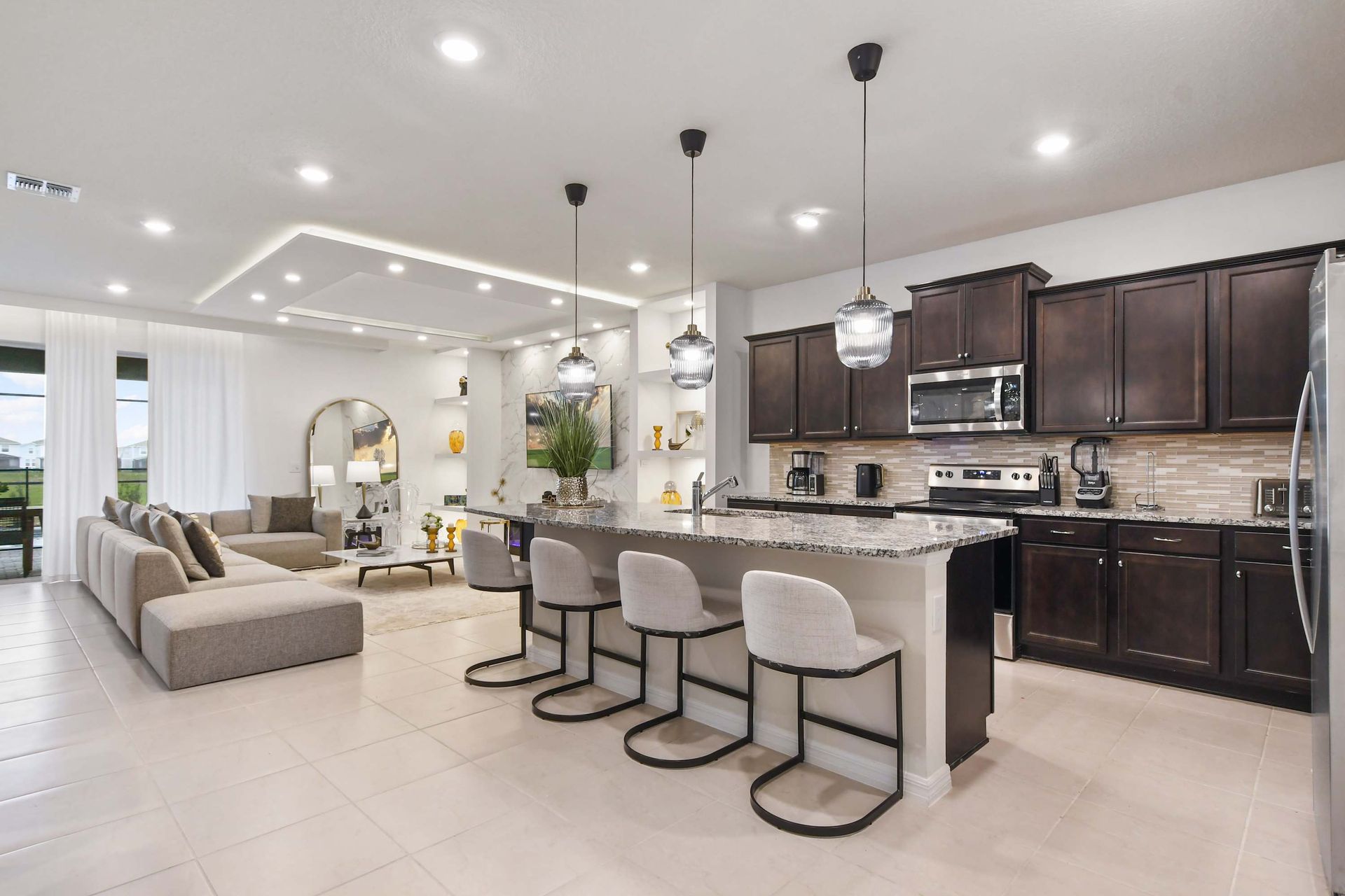 Stylish open kitchen with granite island, pendant lighting, and modern dark cabinetry.