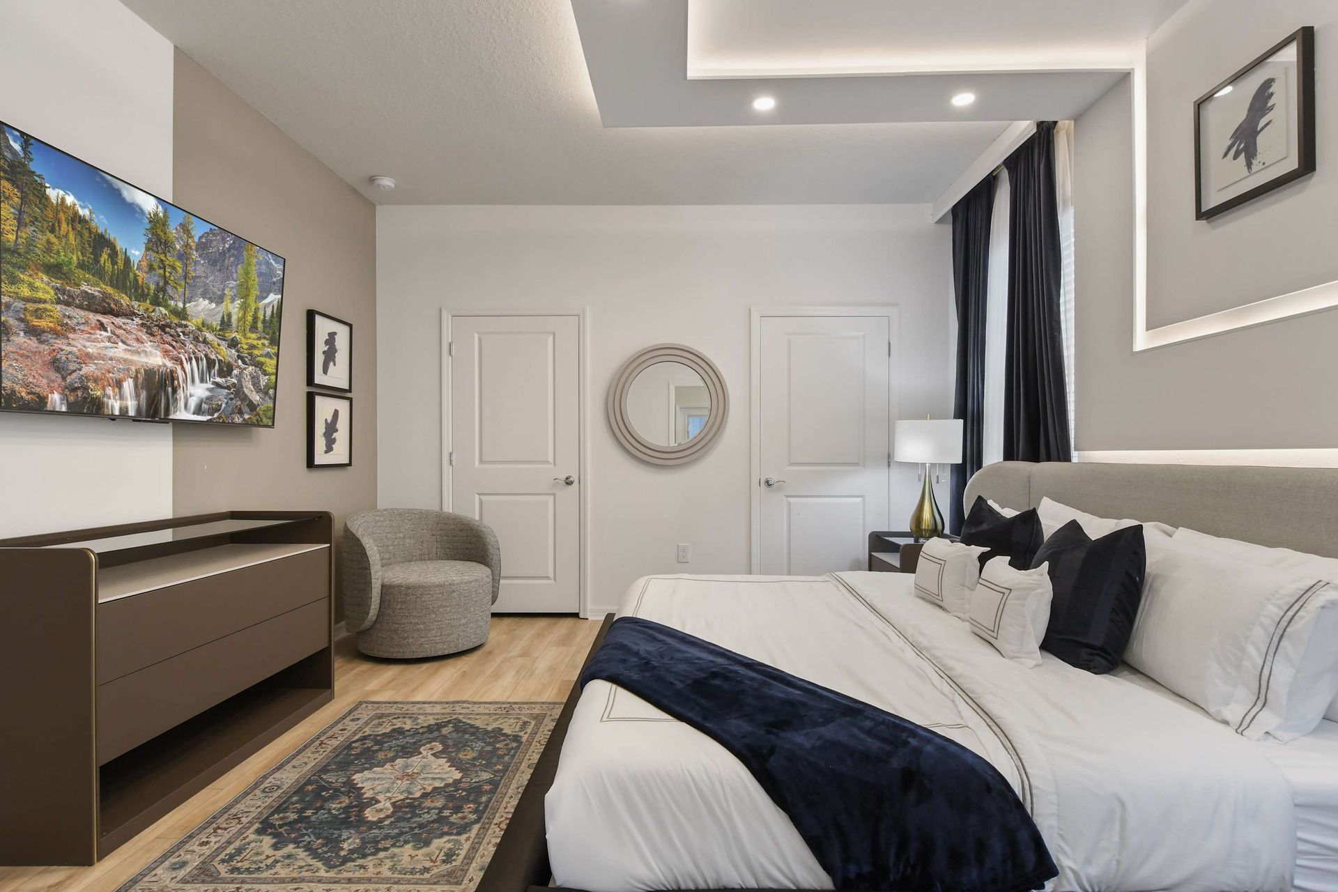 Sophisticated king bedroom with sleek decor, smart TV, and artistic modern touches.
