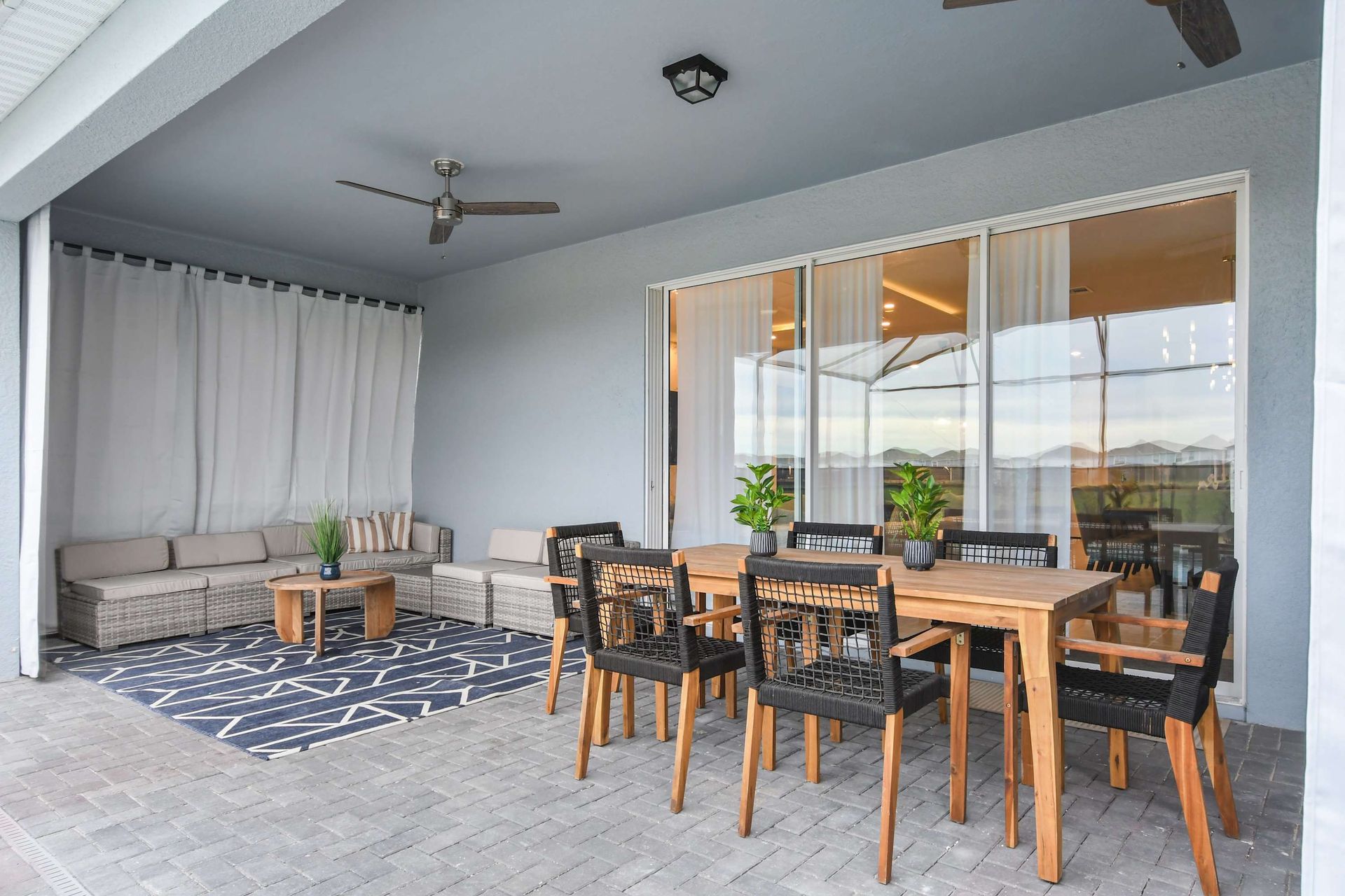 Spacious covered patio with dining area, lounge seating, and serene pool views.
