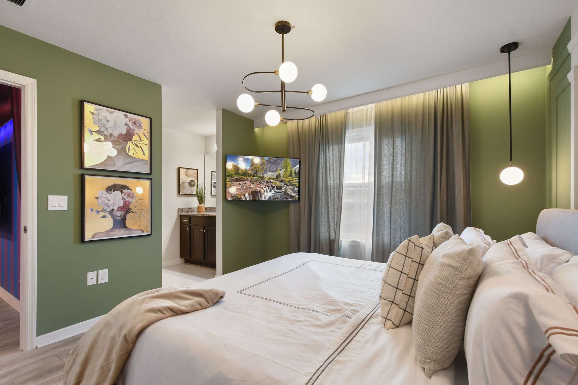 Chic green-accented bedroom with modern lighting, cozy bedding, and ensuite vanity area.
