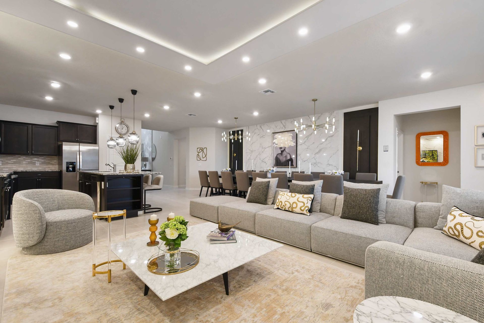 Spacious designer living room with luxe seating, open kitchen, and elegant lighting.