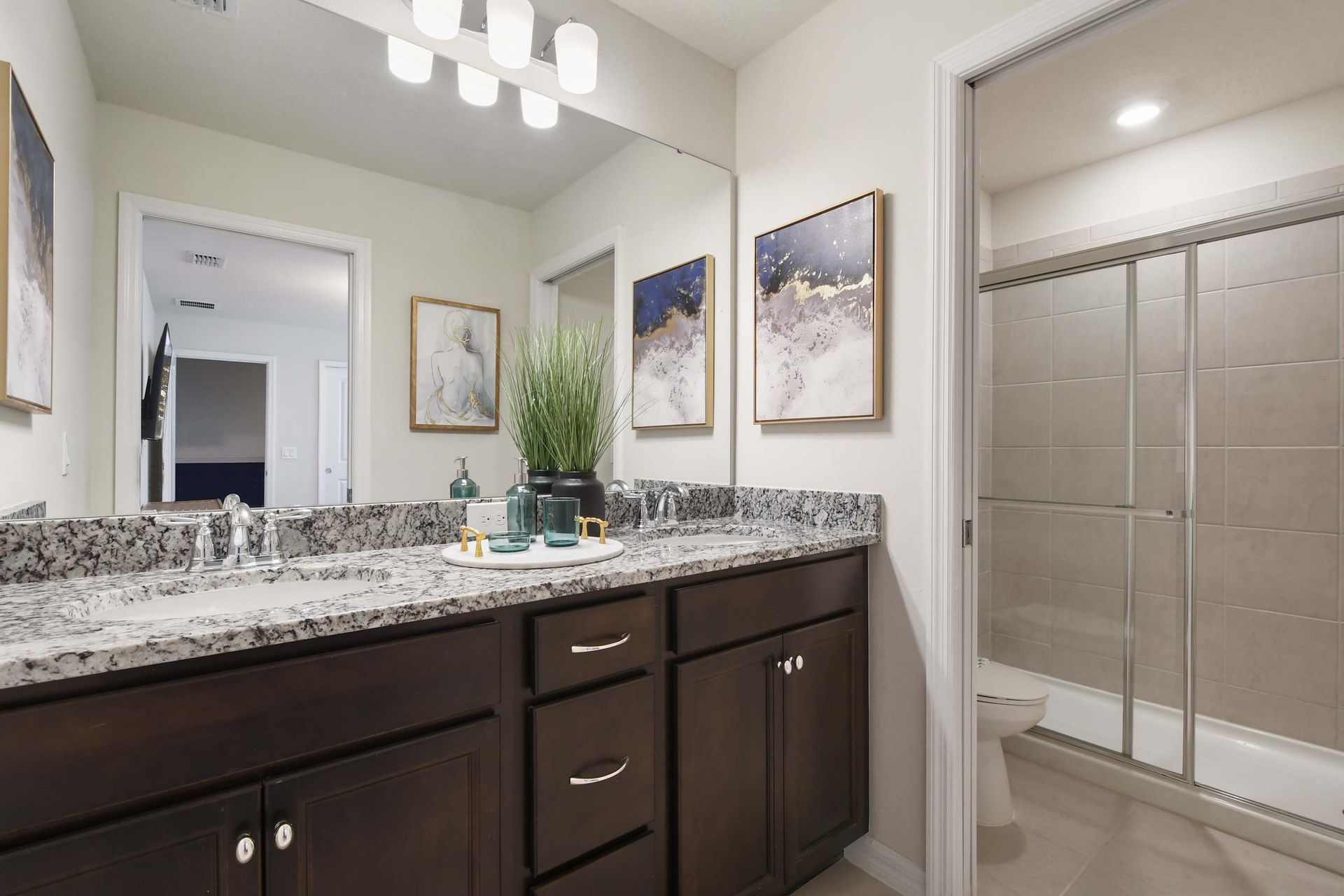 Modern bathroom with granite counters, double sinks, and a sleek glass shower.