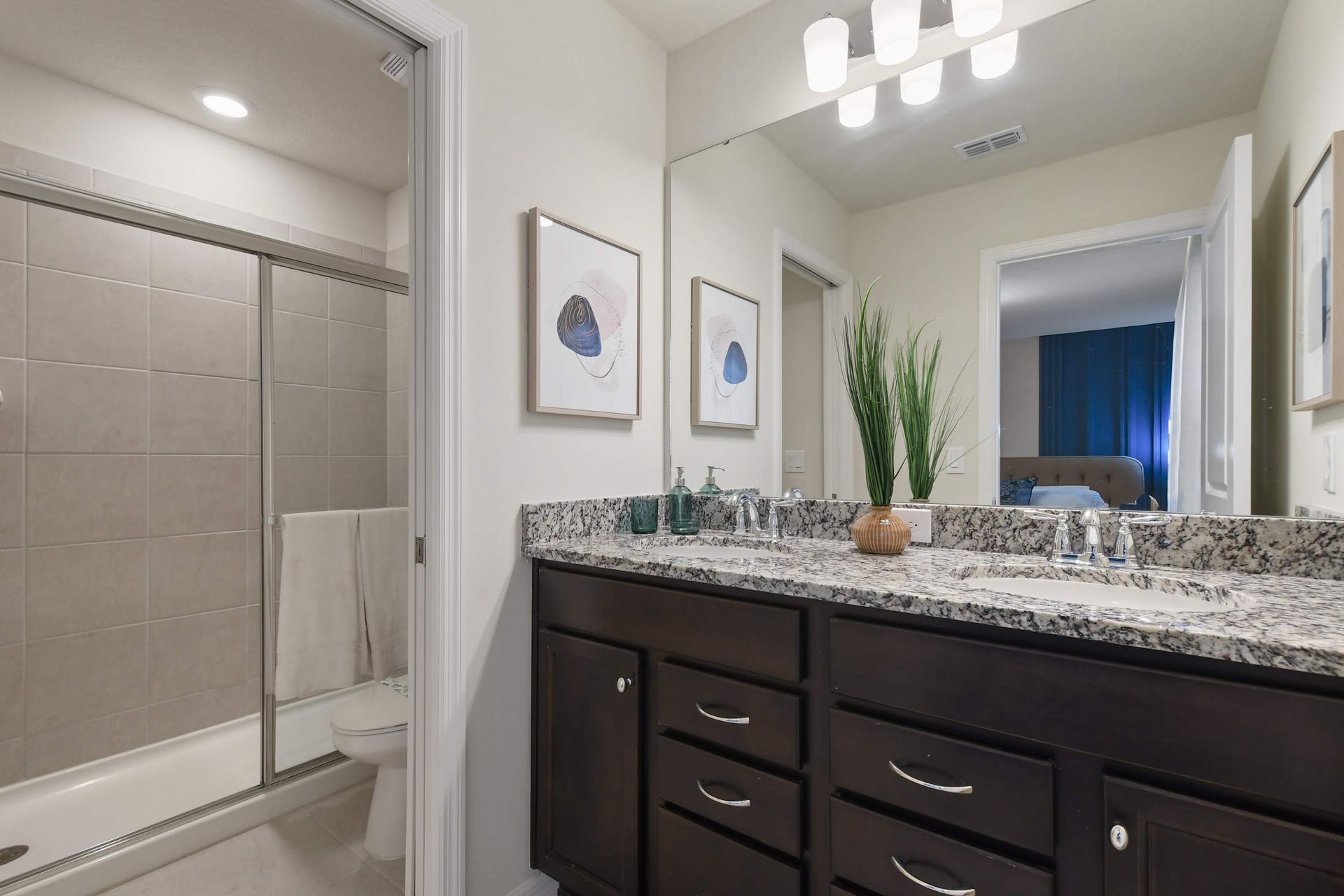 Elegant bathroom with granite counters, double vanity, and tiled glass shower.
