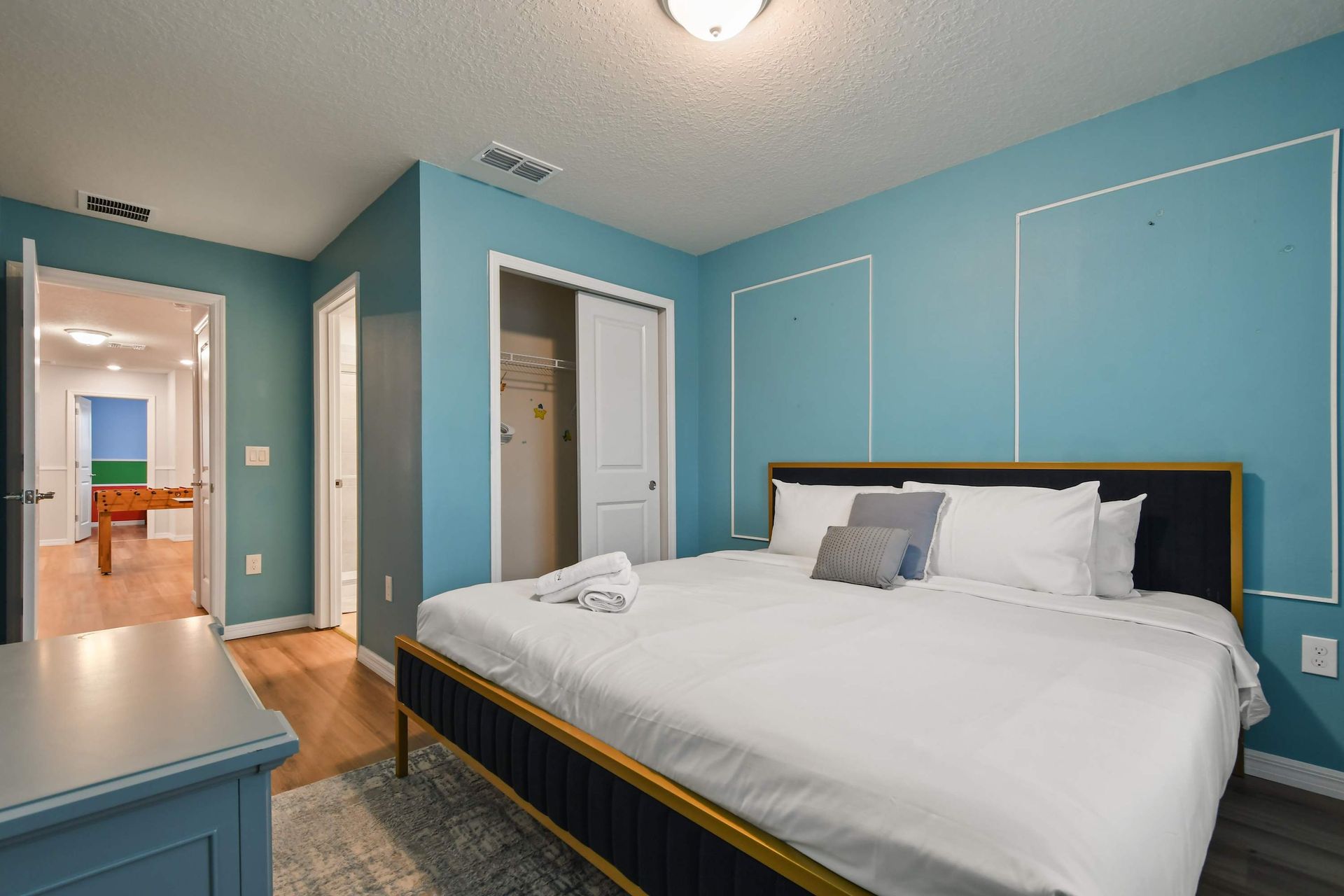 Chic blue bedroom with king bed, ensuite access, and view of game room fun.