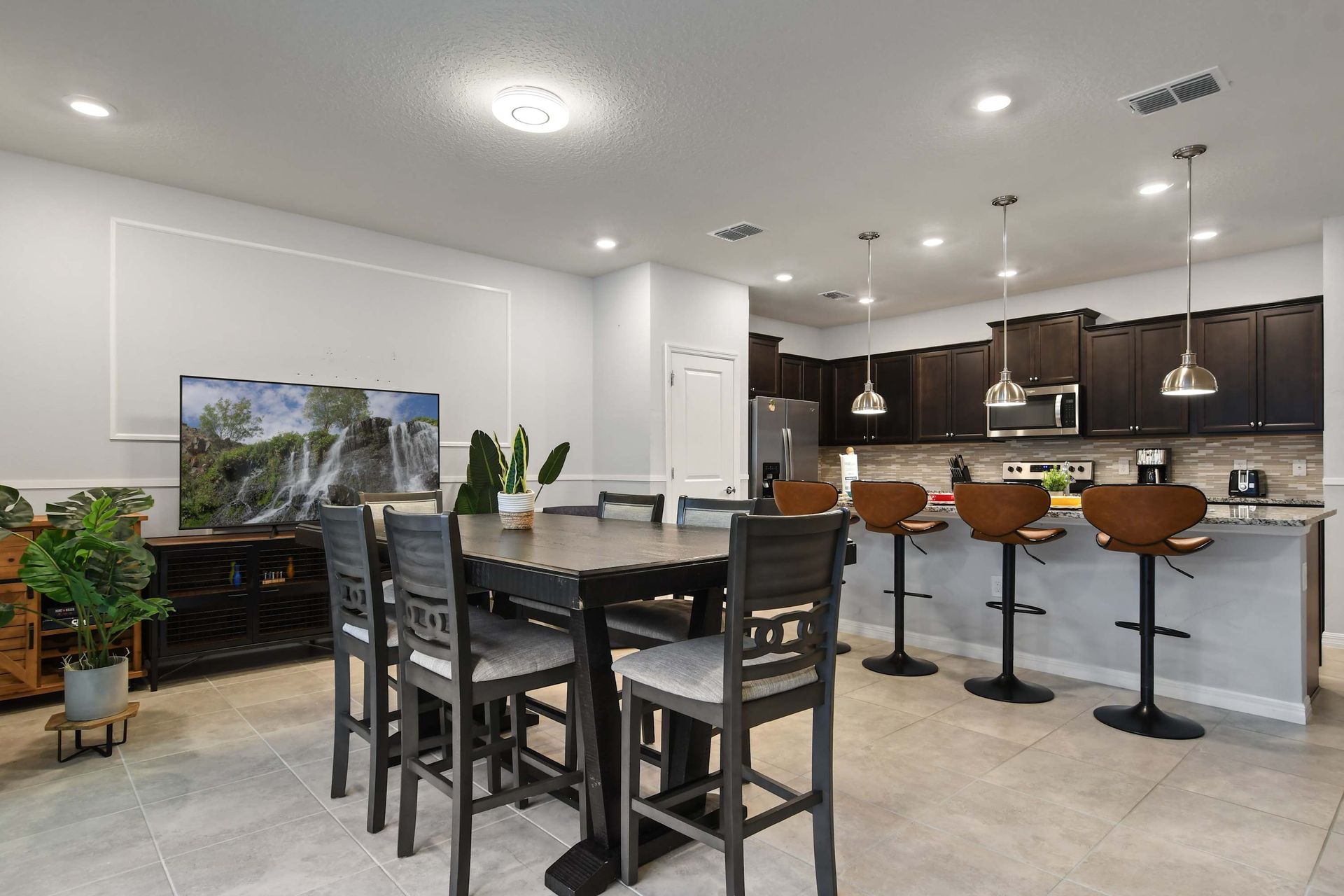 Spacious dining and kitchen area with bar seating and a large flat-screen TV.