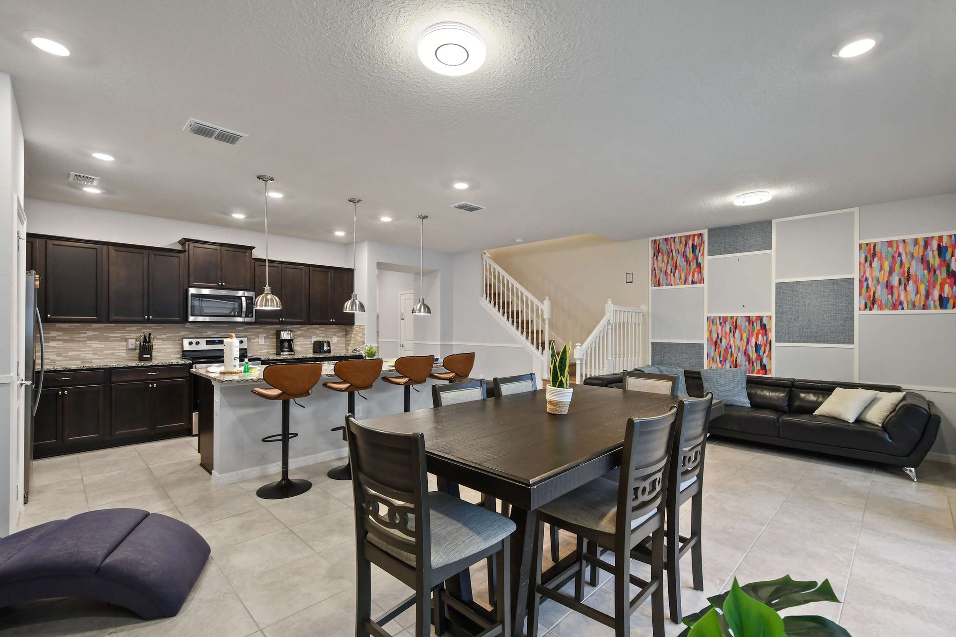 Modern open layout with dining, bar seating, and a cozy lounge near the staircase.