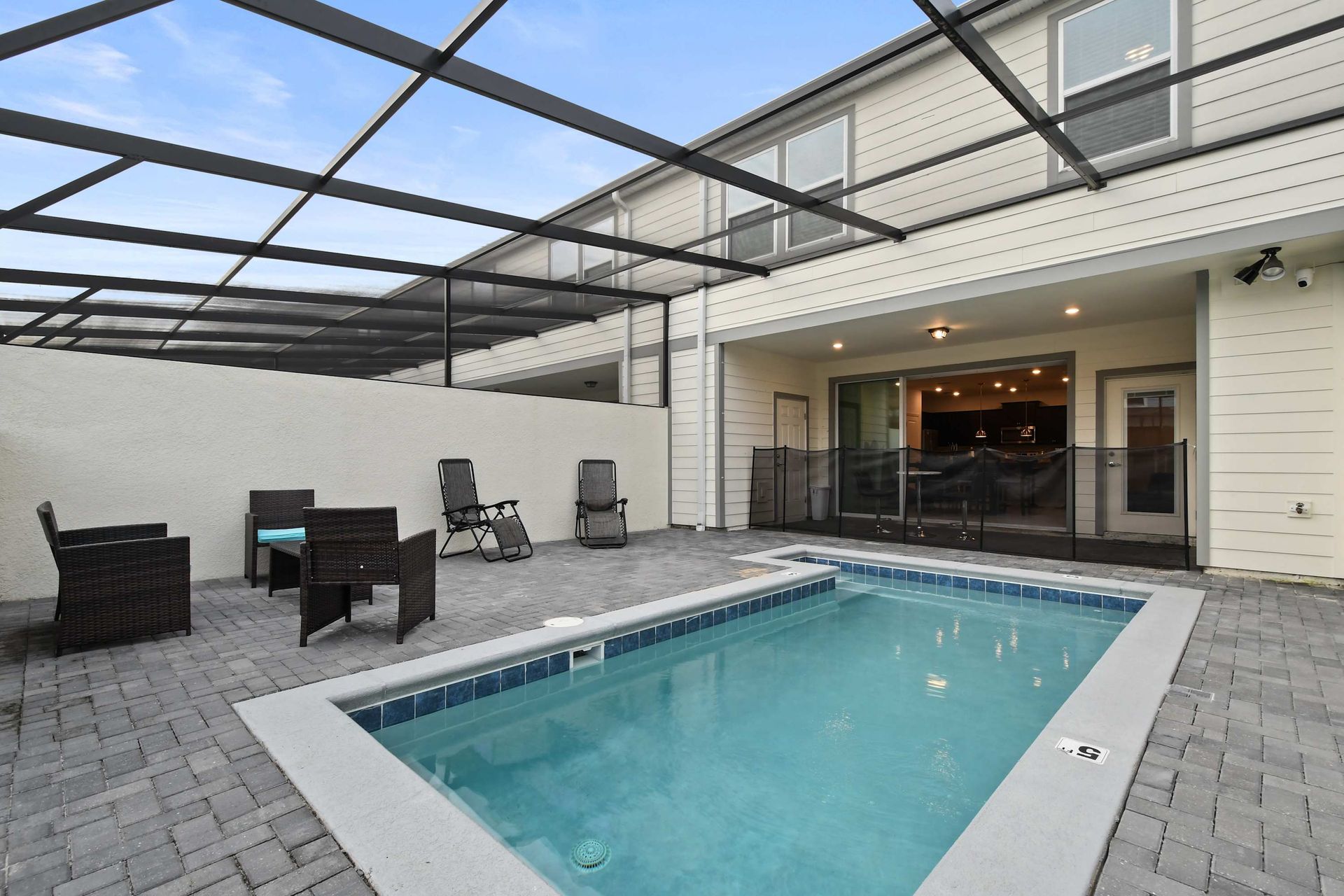 Spacious screened patio with private pool, safety fence, and outdoor seating area.