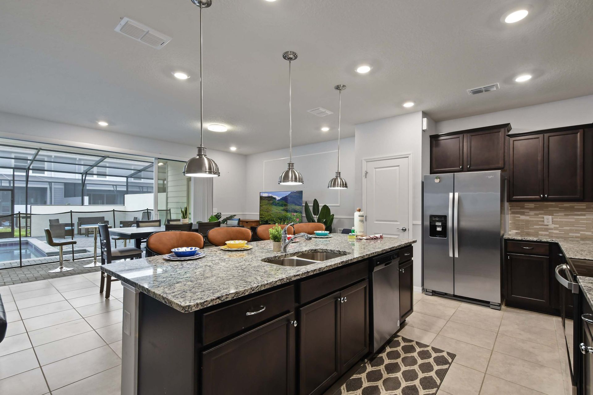 Bright open kitchen with pool views, granite island, and stainless appliances.