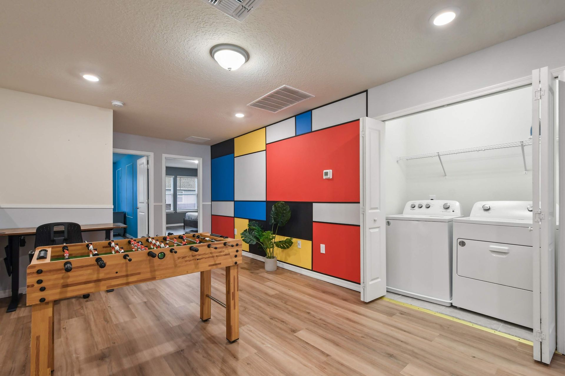 Game loft with foosball, work desk, laundry, and bold geometric accent wall.