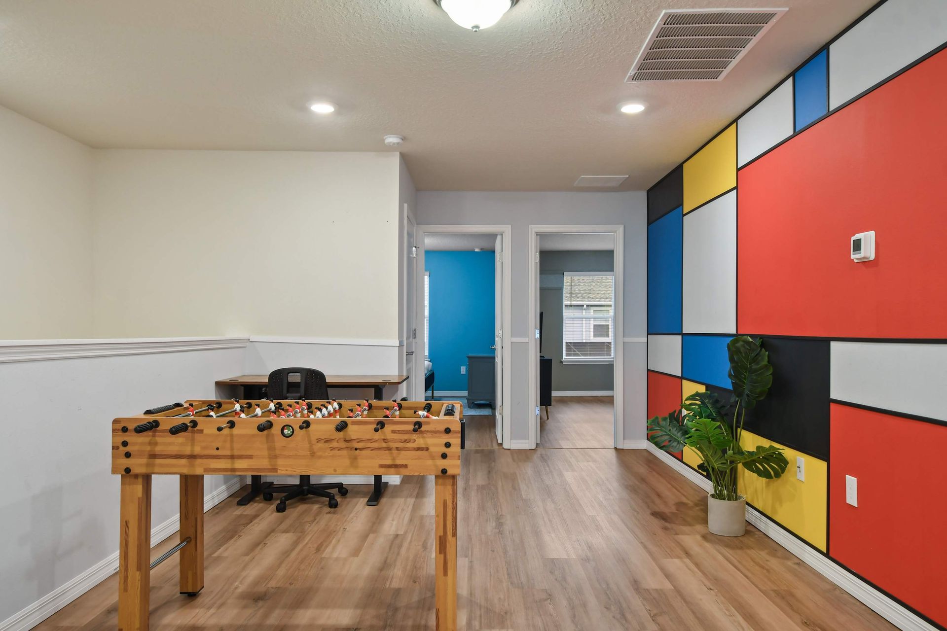Colorful game loft with foosball table, workspace, and bold modern art wall.