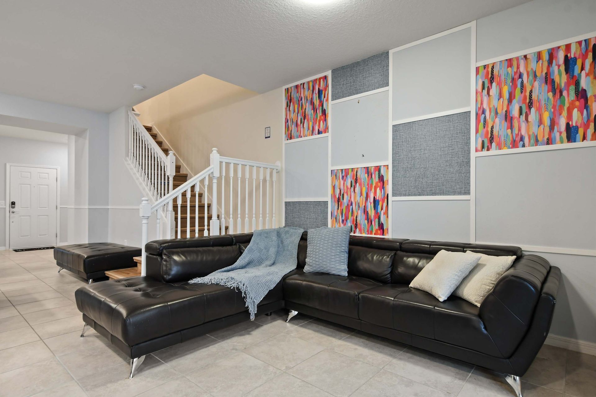 Spacious lounge with a sleek leather sectional and vibrant modern accent wall.