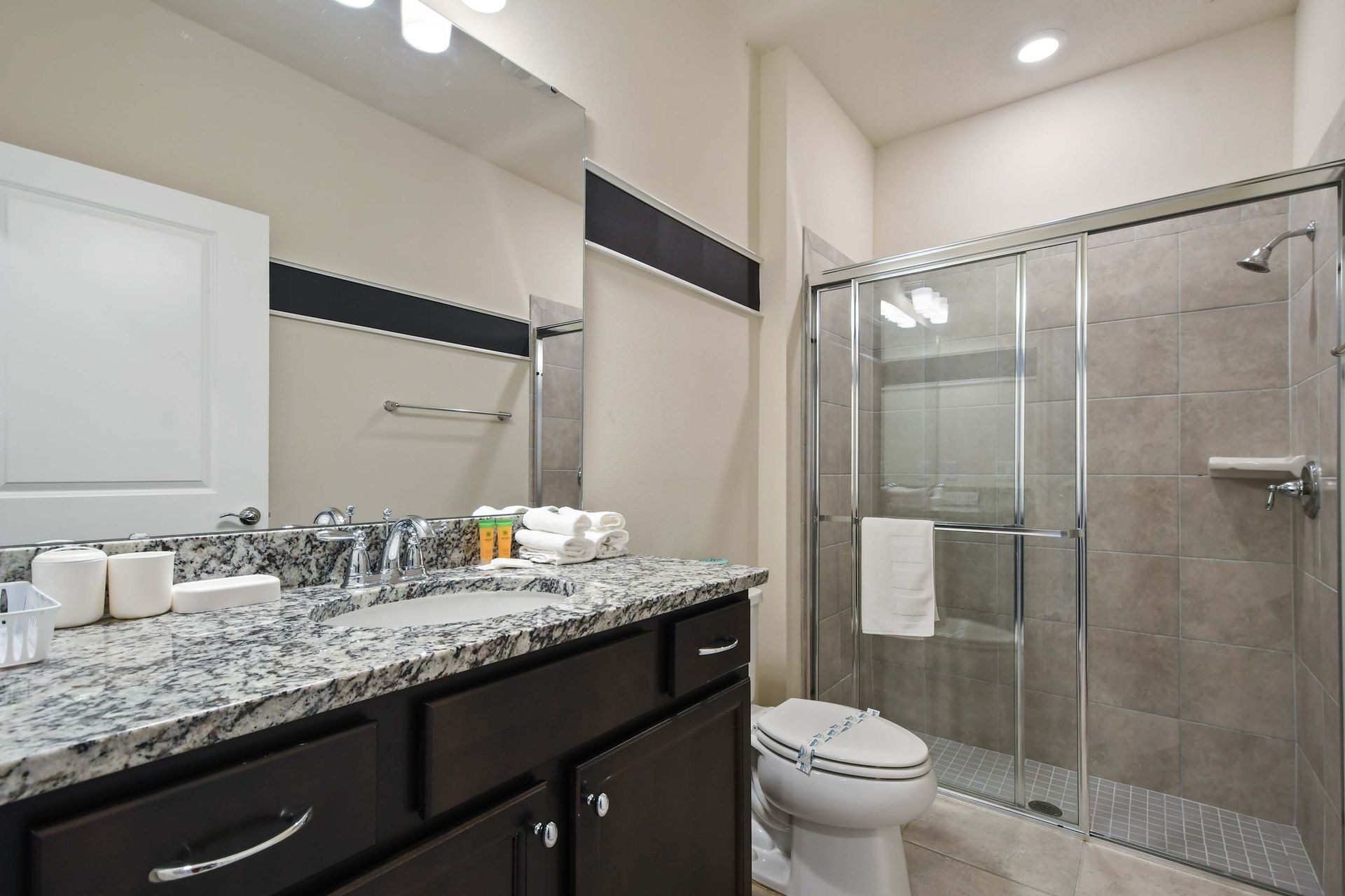 Stylish bathroom with granite vanity, glass walk-in shower, and sleek finishes.