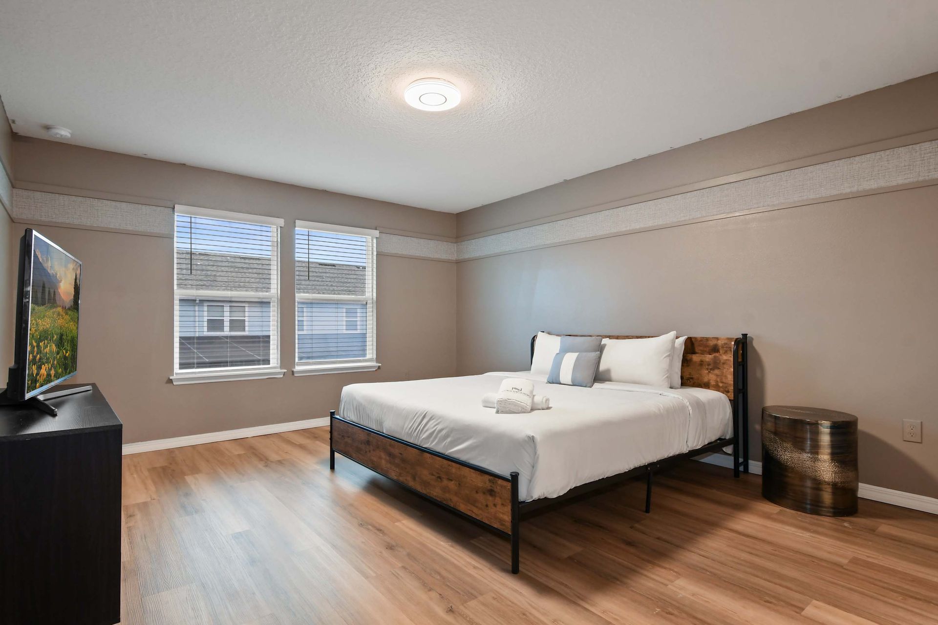Spacious bedroom with king bed, natural light, smart TV, and modern decor.