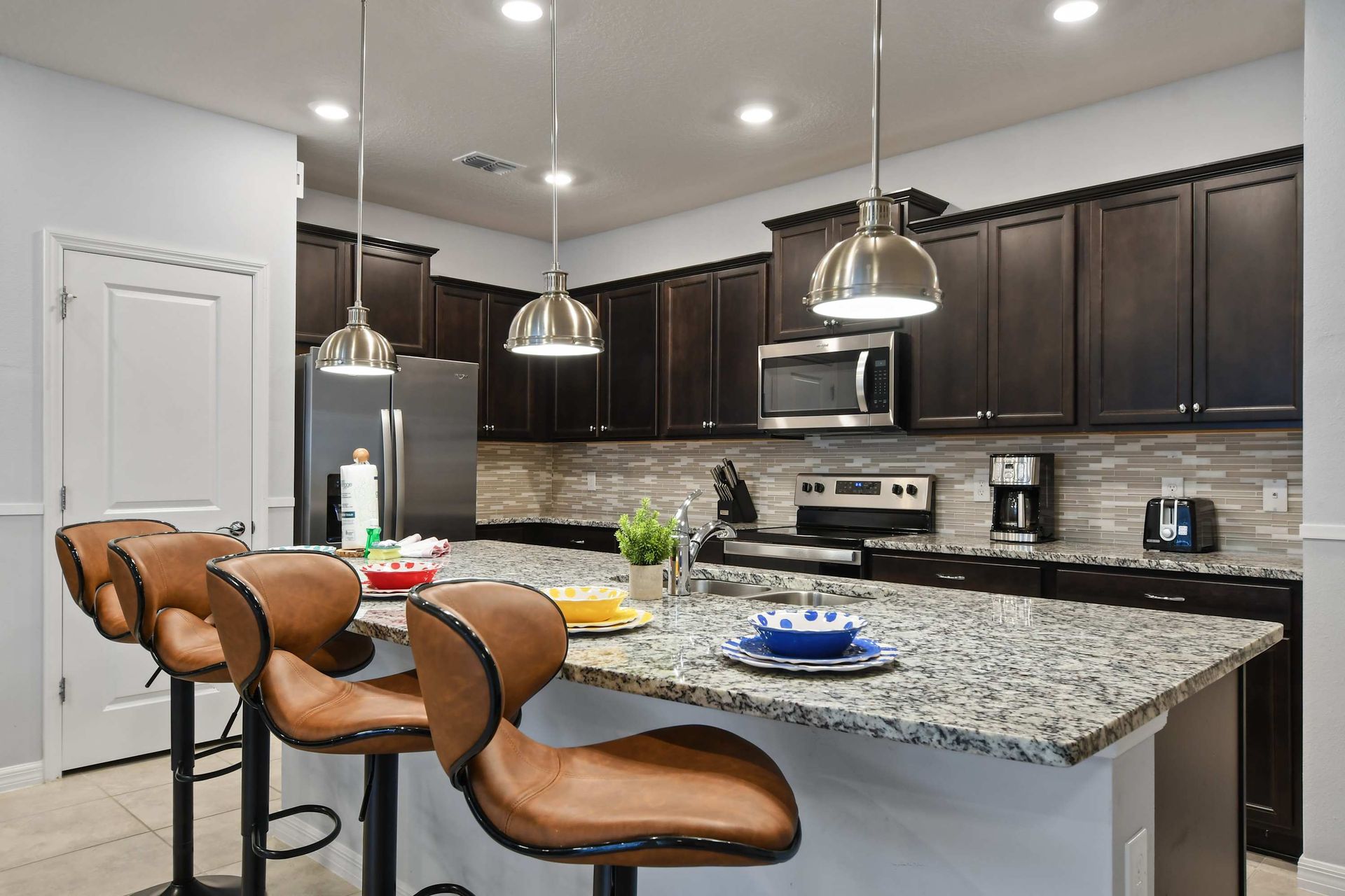 Chic granite island with leather bar stools, perfect for casual meals or cocktails.