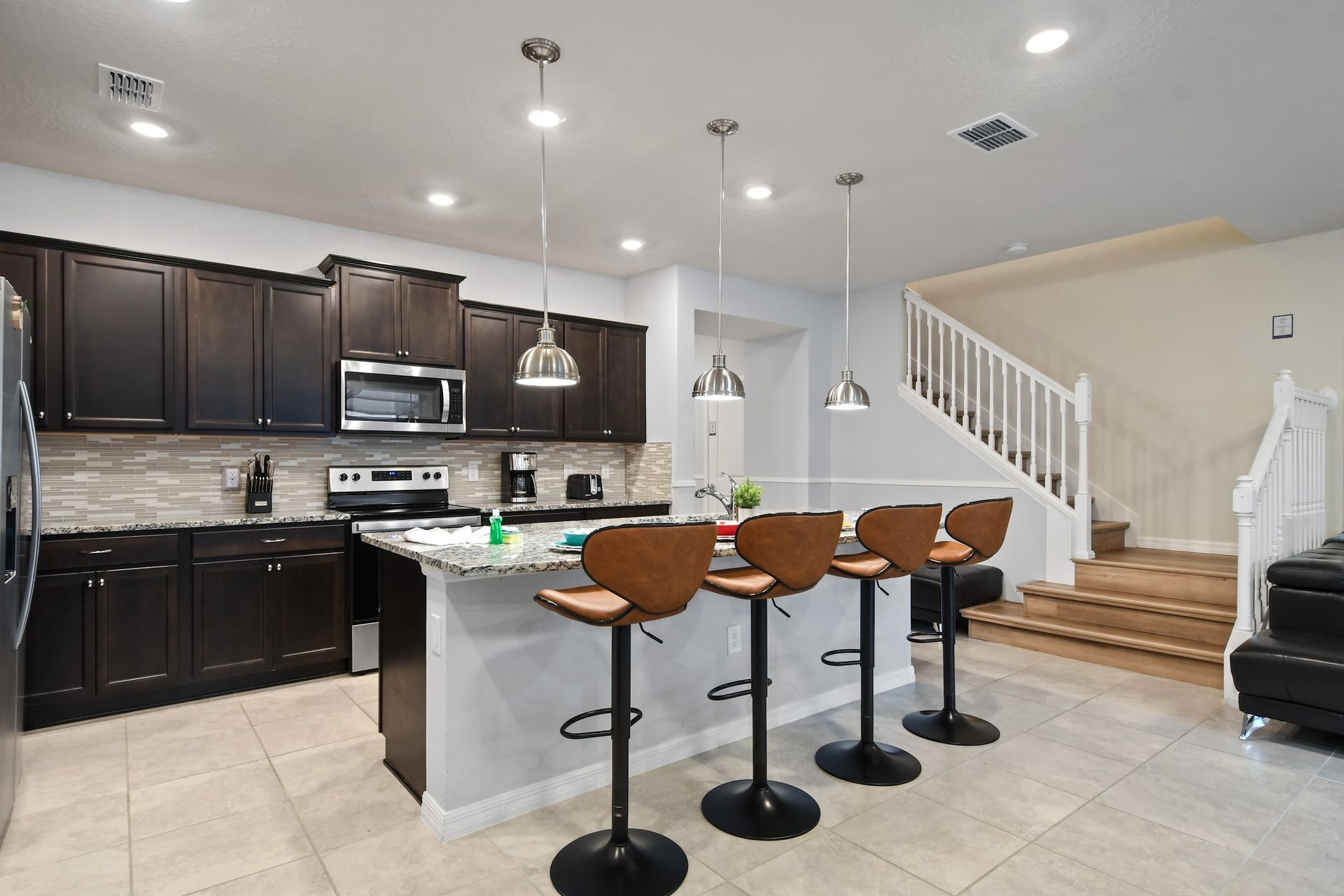 Sleek kitchen with granite island, bar seating, and modern pendant lighting.