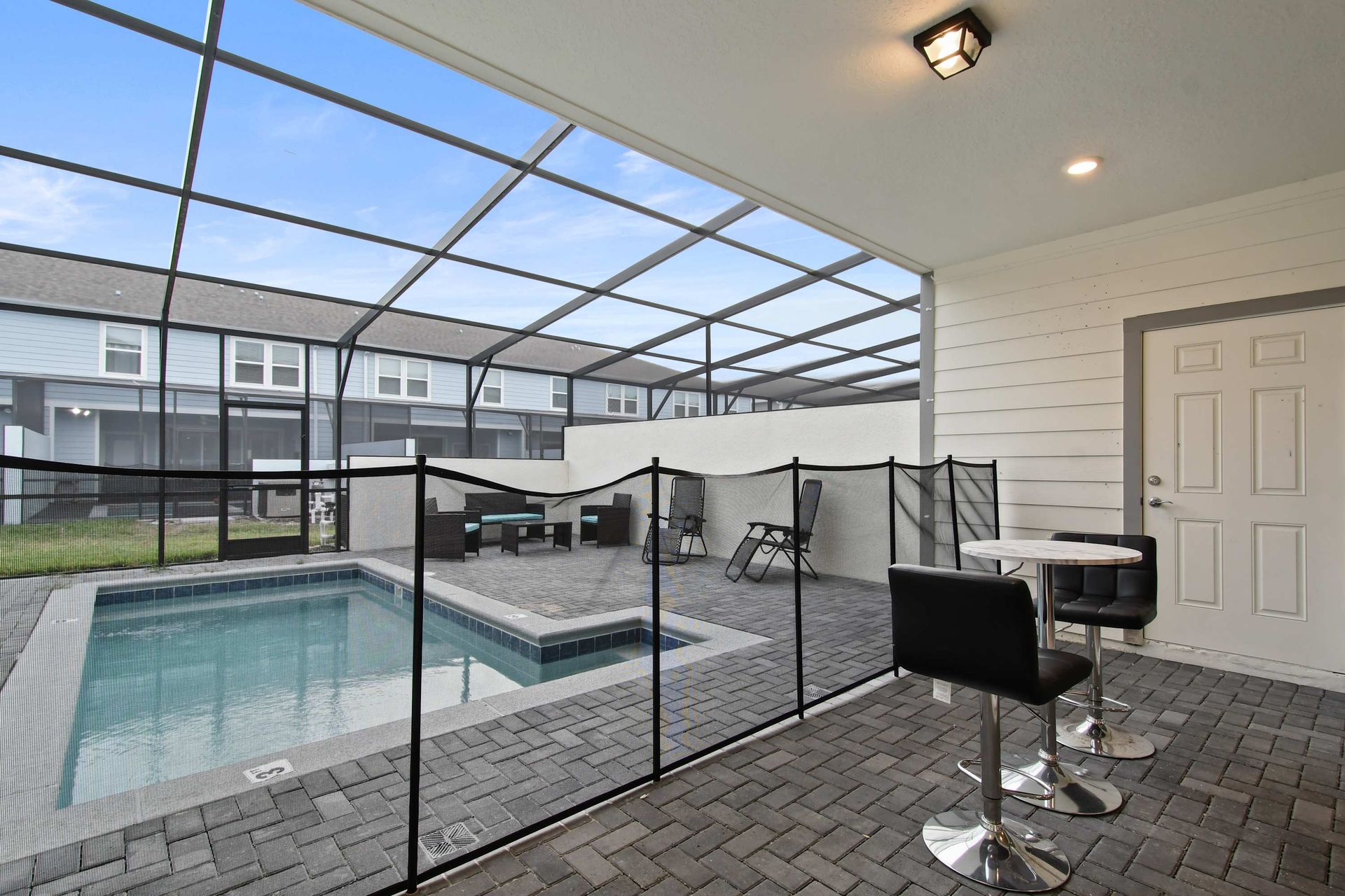 Screened private pool with safety gate, lounge seating, and covered patio dining.