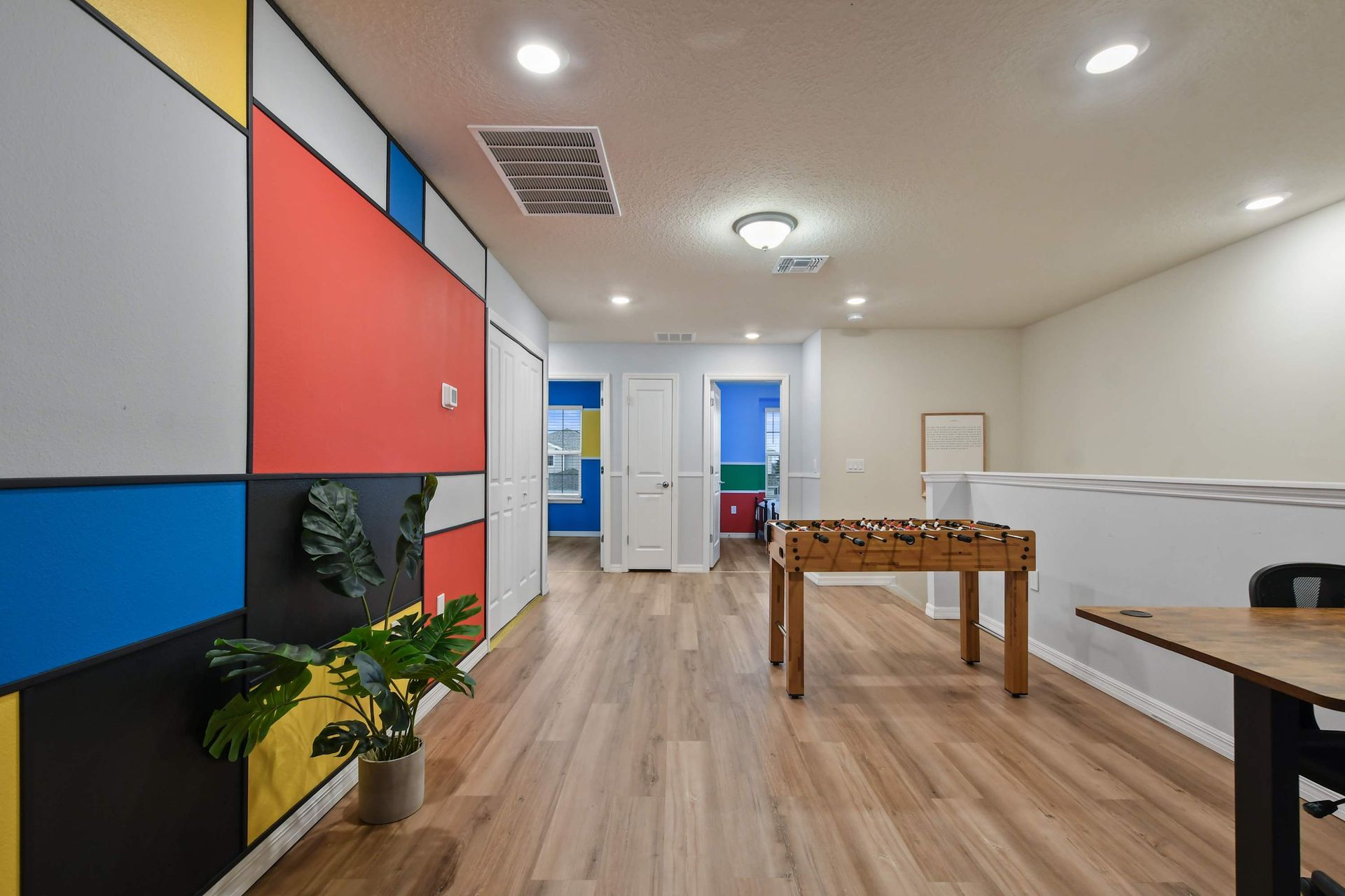 Upstairs game loft with foosball, colorful mural wall, and work-from-home setup.