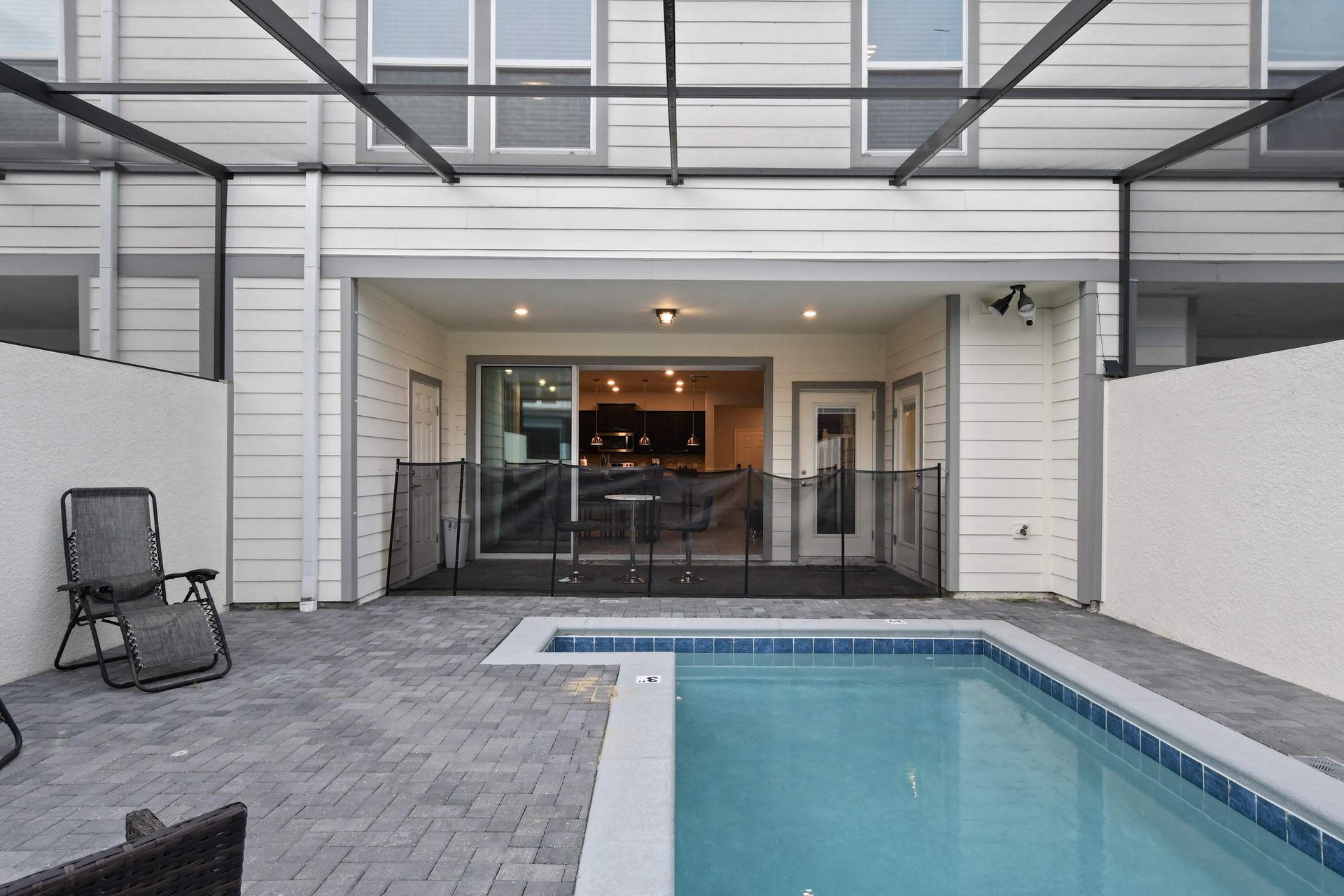 Covered patio with poolside seating, safety fence, and seamless indoor access.