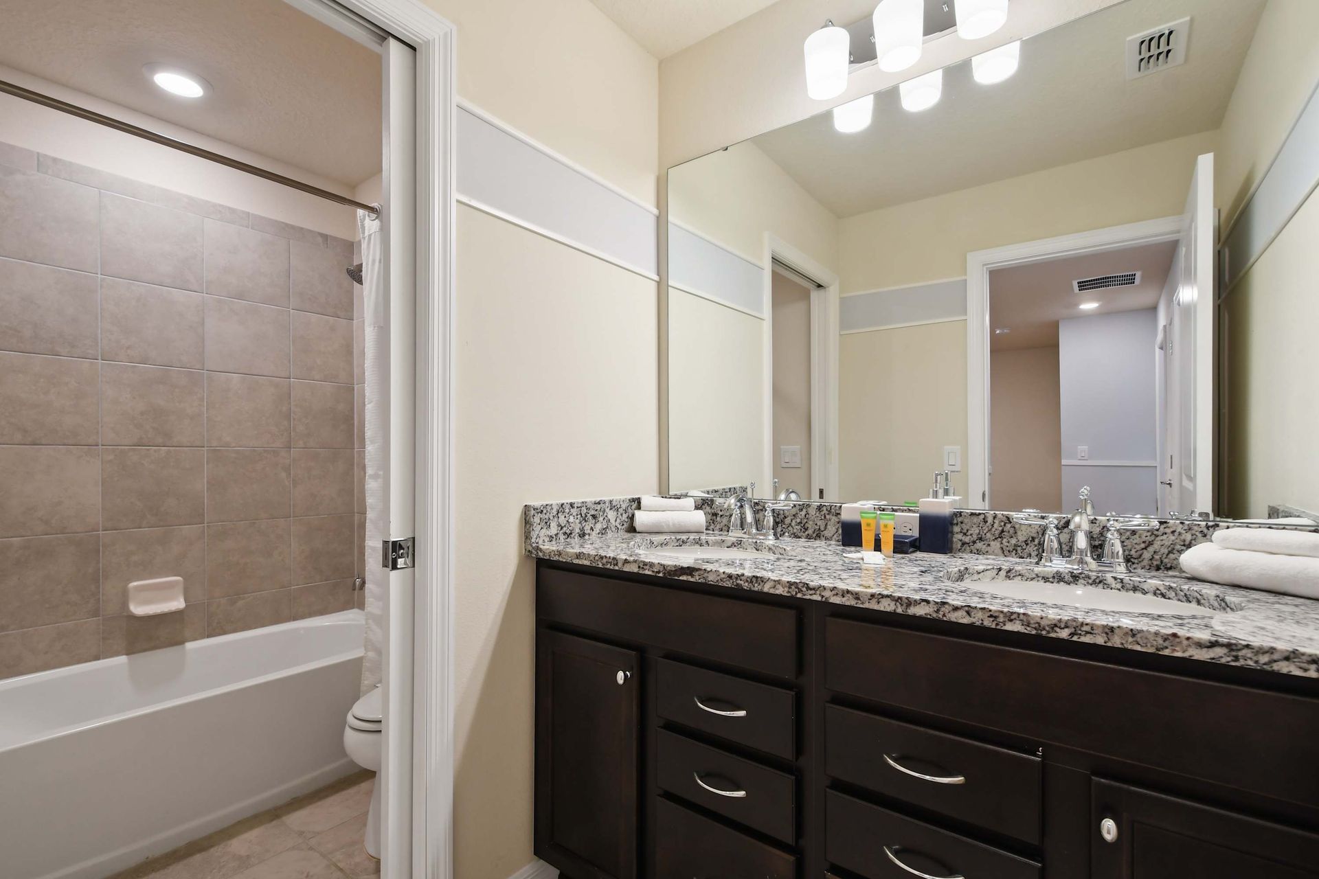 Elegant bathroom with dual granite sinks, full tub, and modern lighting accents.