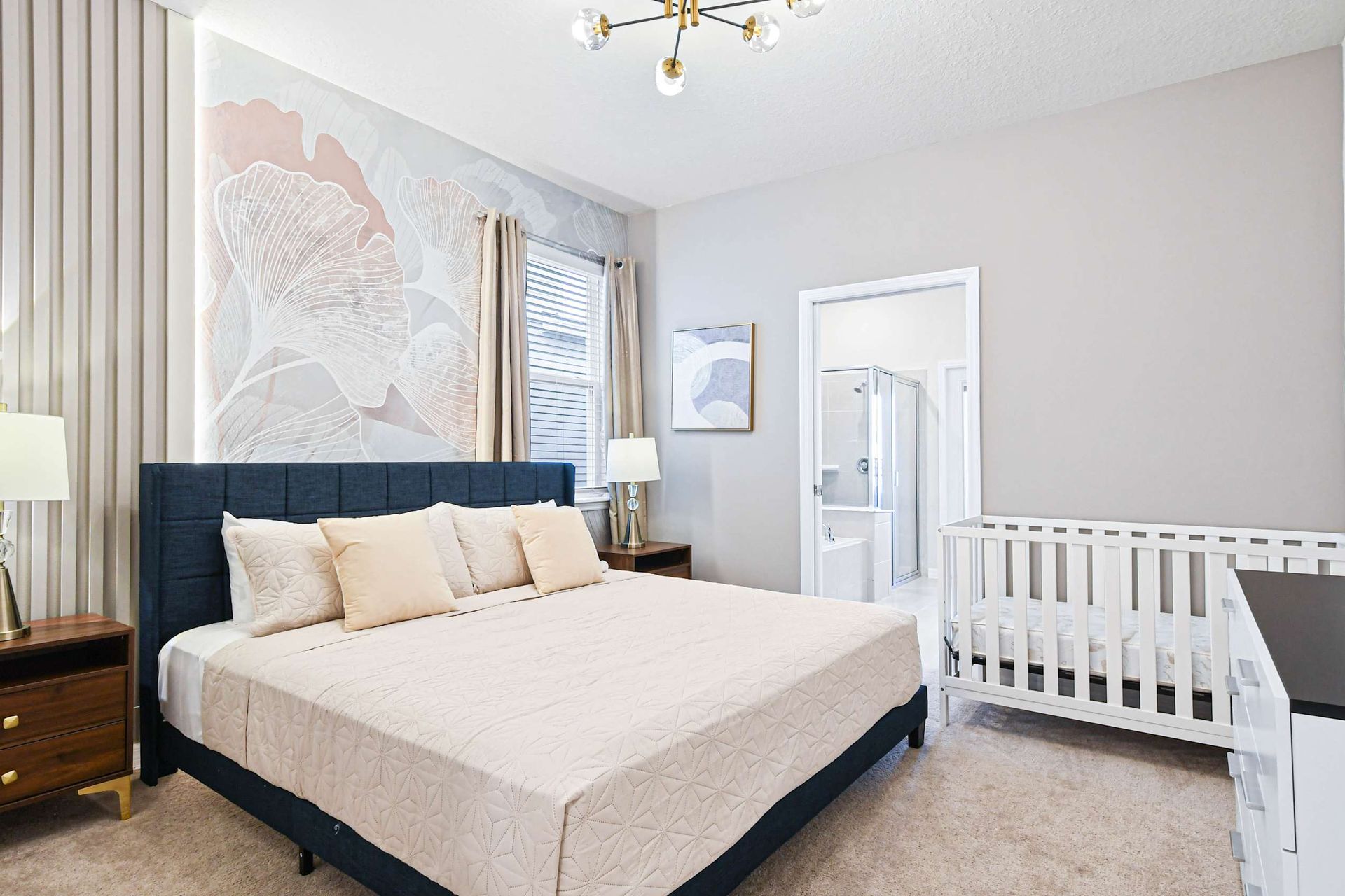 Serene master suite with king bed, stylish decor, ensuite bath, and crib setup.