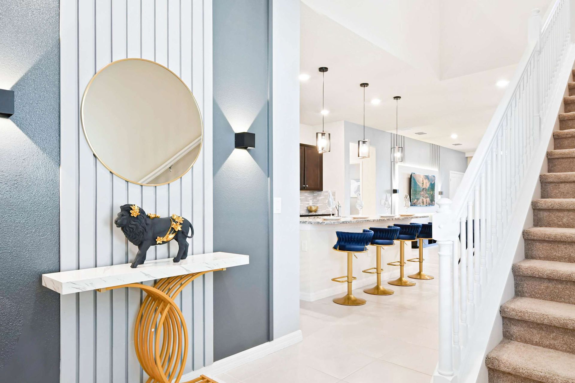 Stylish entryway with gold accents, modern decor, and view into luxe kitchen.