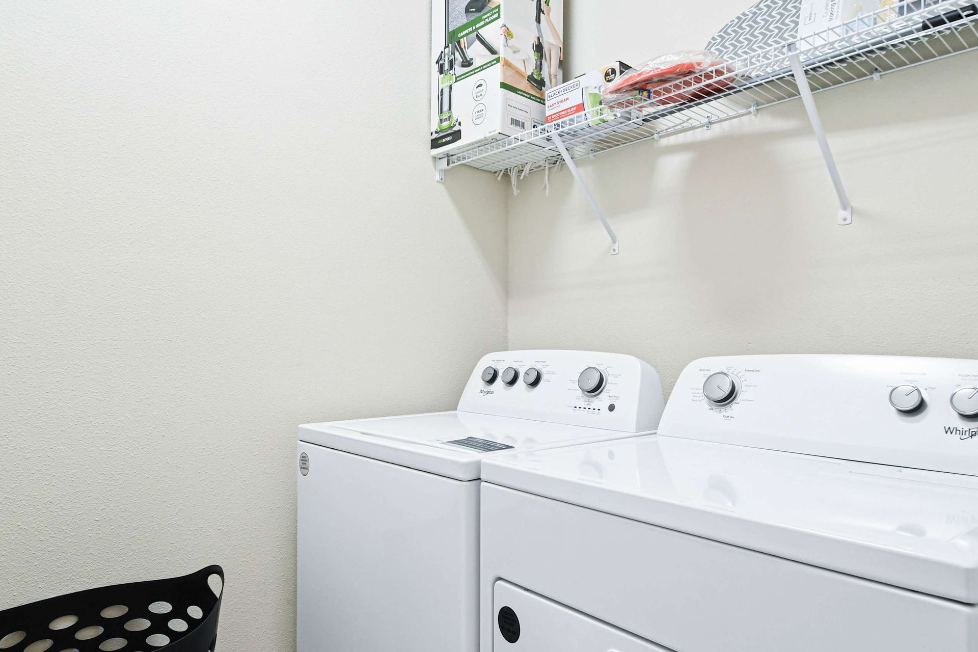 Laundry room with Whirlpool washer and dryer, shelving, and essentials ready.