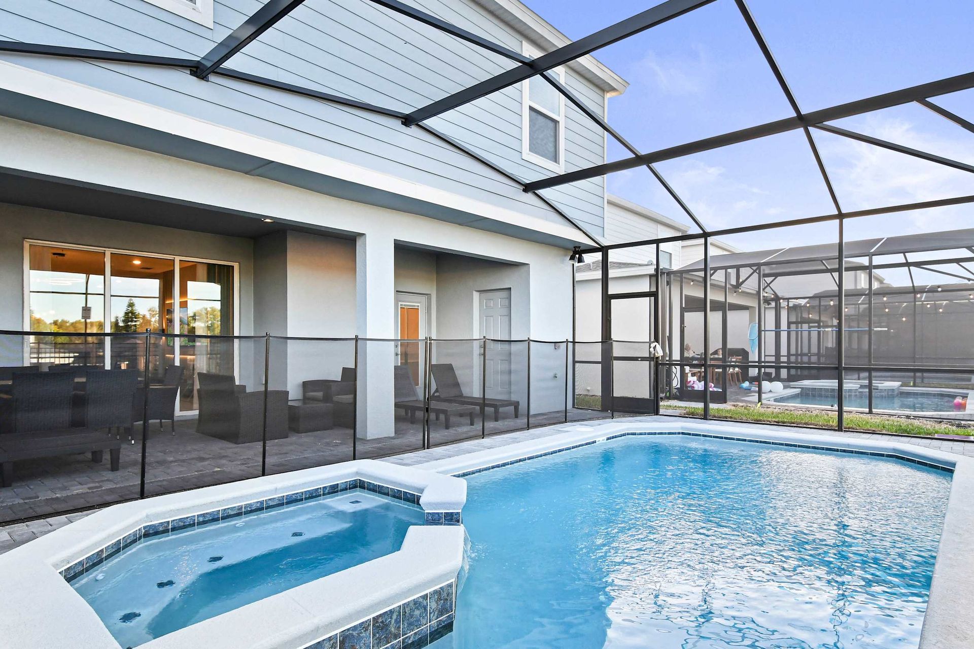 Private screened pool and spa with lounge seating and covered dining space.
