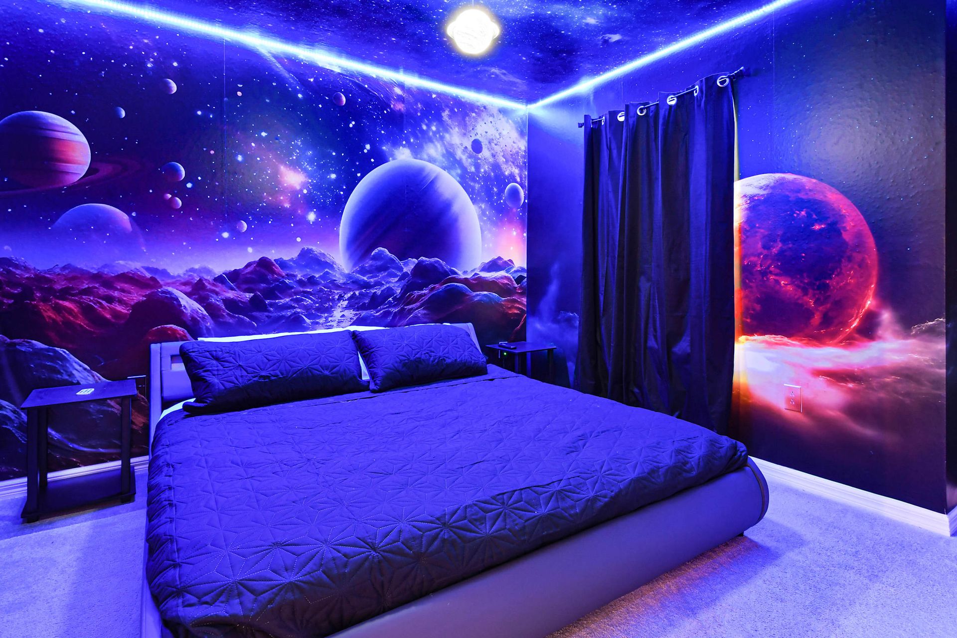Cosmic-themed bedroom with glowing galaxy walls and a king bed under the stars.