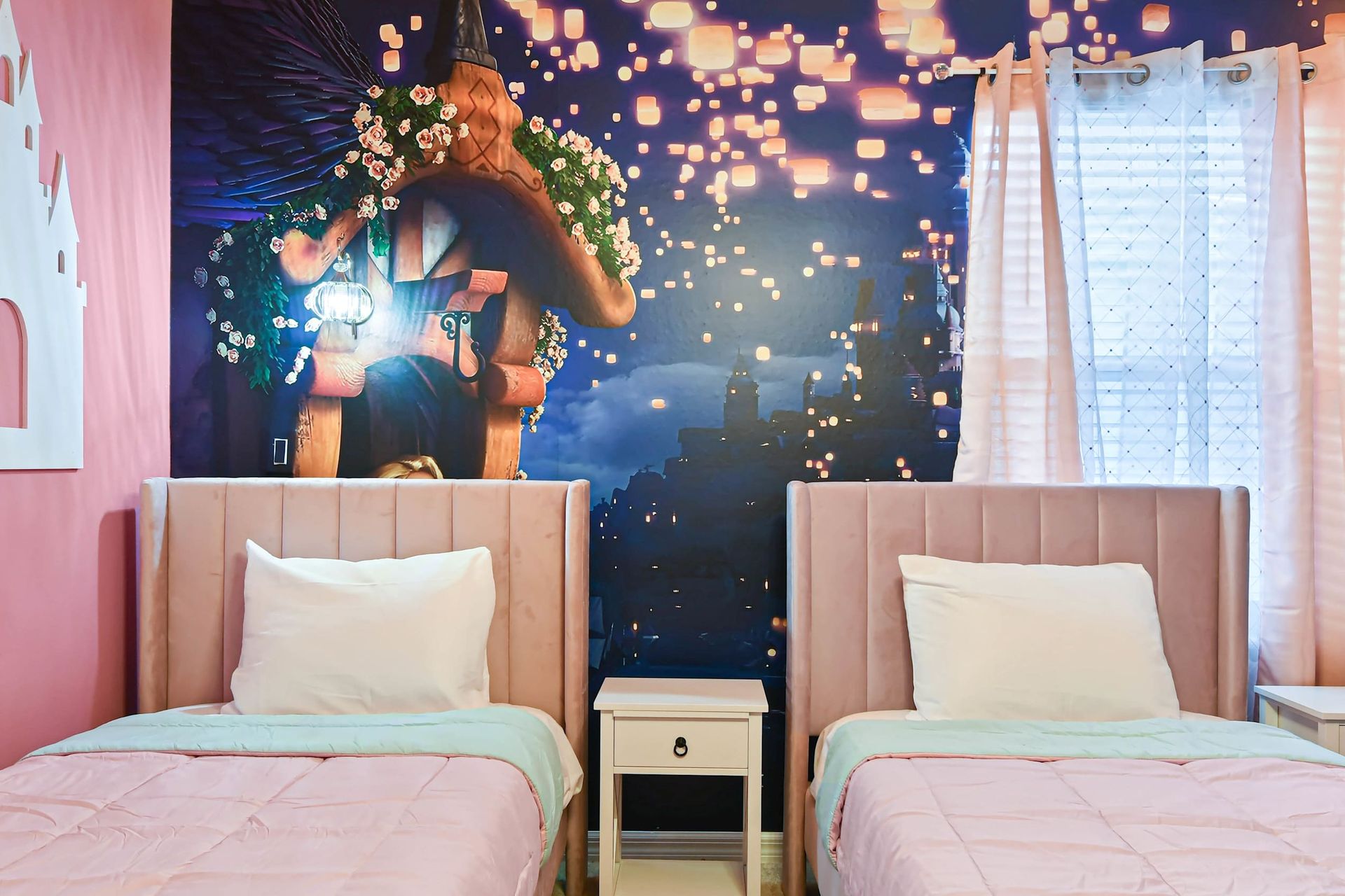 Charming fairytale room with twin pink beds, castle decor, and lantern mural.