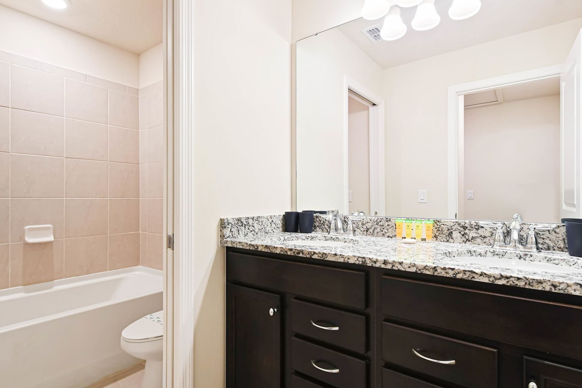 Modern bathroom with granite vanity, full tub, and bright, stylish finishes.