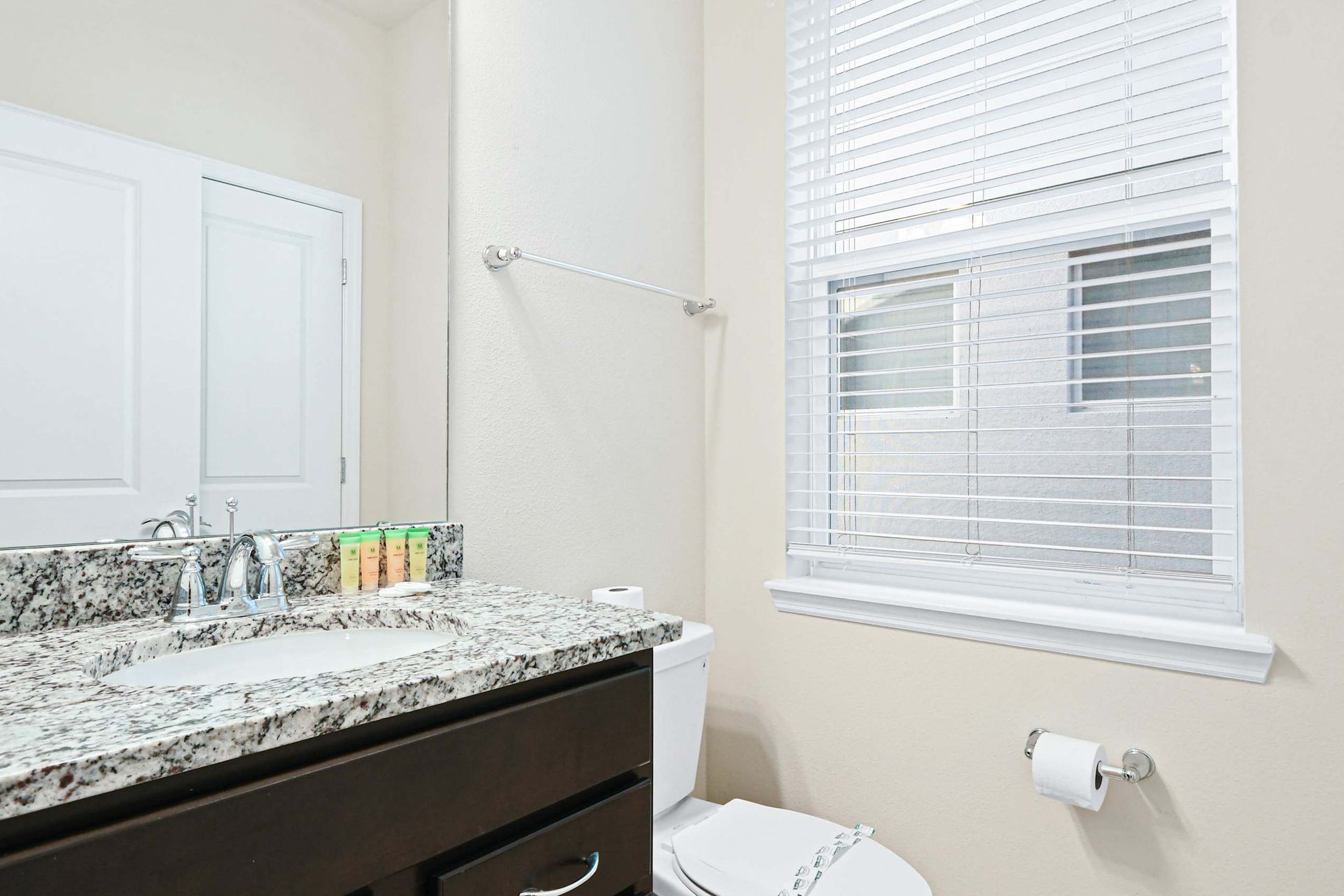 Bright and clean bathroom with granite countertop and natural light window.