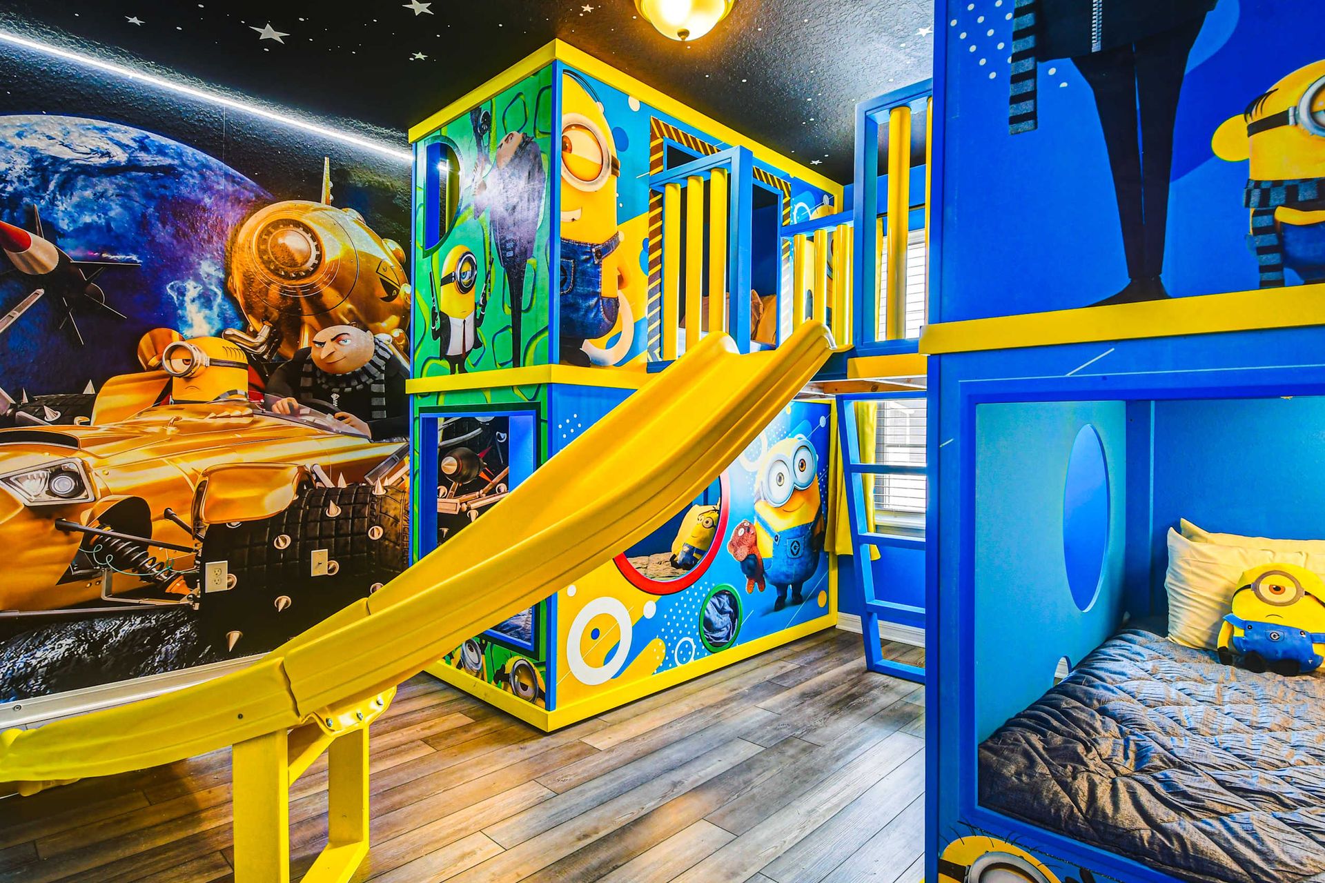 Minion adventure room with custom slide, space-themed mural, and cozy bunk beds.