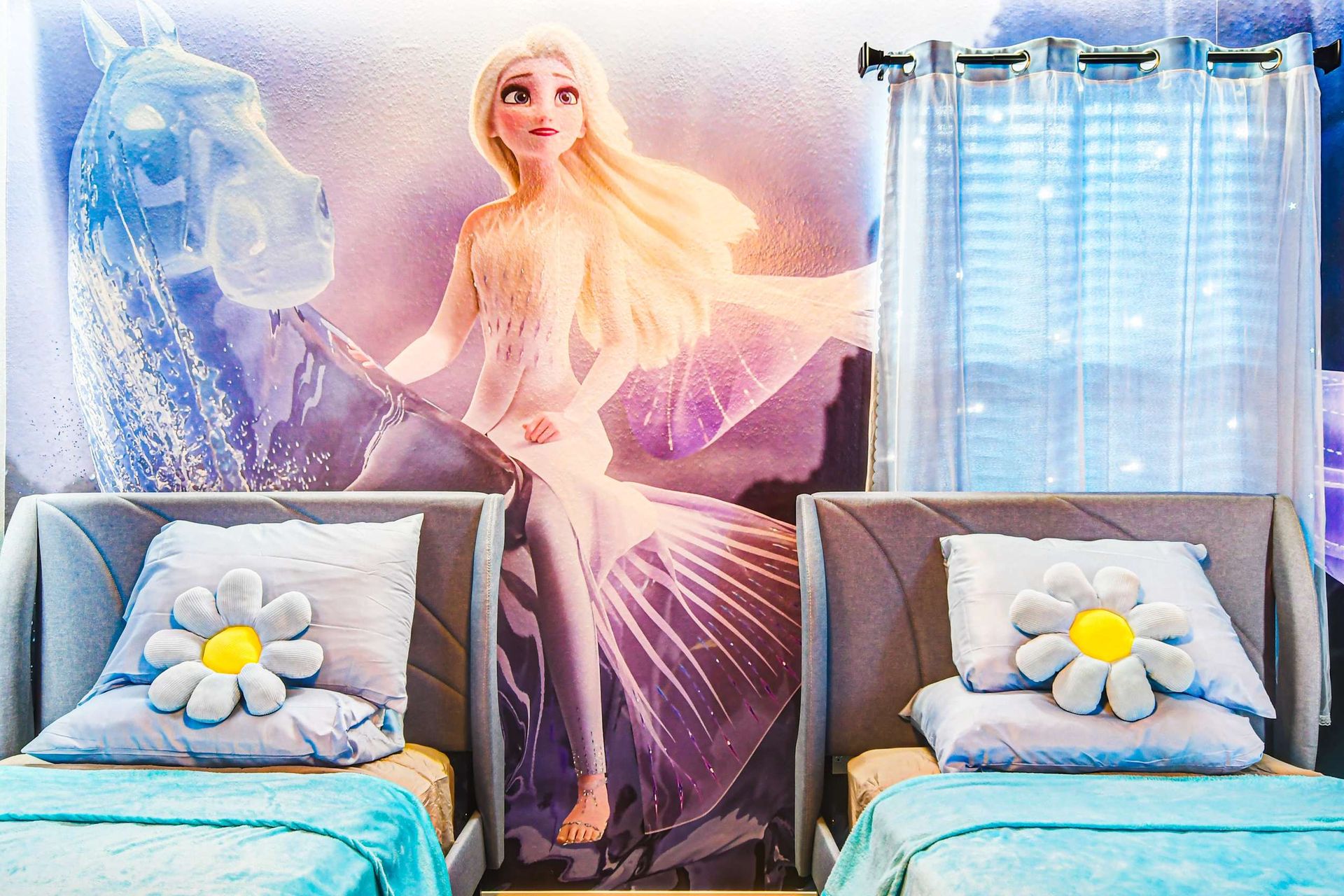 Enchanting Frozen room with shimmering lights, icy murals, and cozy twin beds.
