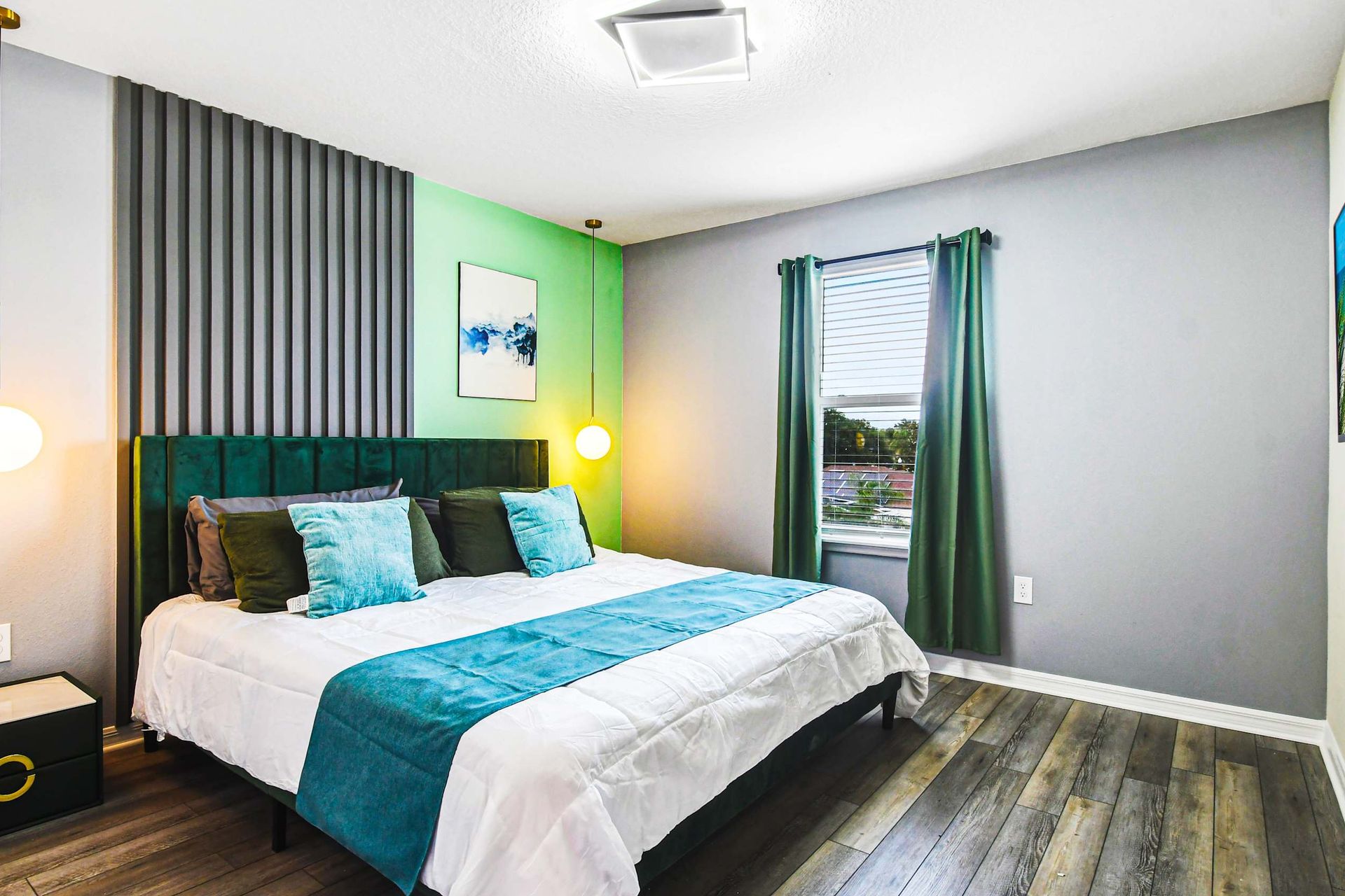 Chic bedroom with king bed, accent wall, pendant lights, and a mounted smart TV.