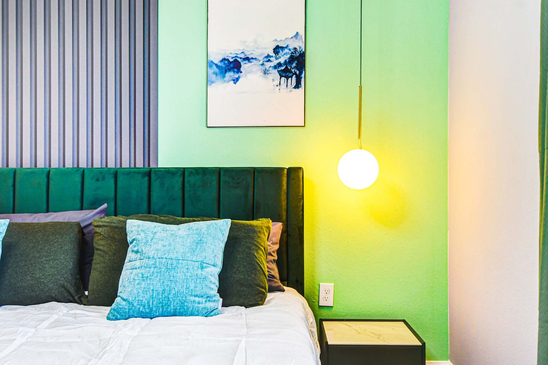 Vibrant bedroom with modern pendant lighting, velvet headboard, and bold color pops.
