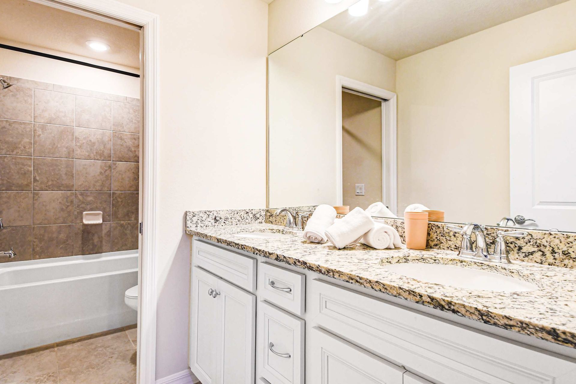 Elegant full bathroom with granite vanity, large mirror, and tiled shower tub combo.
