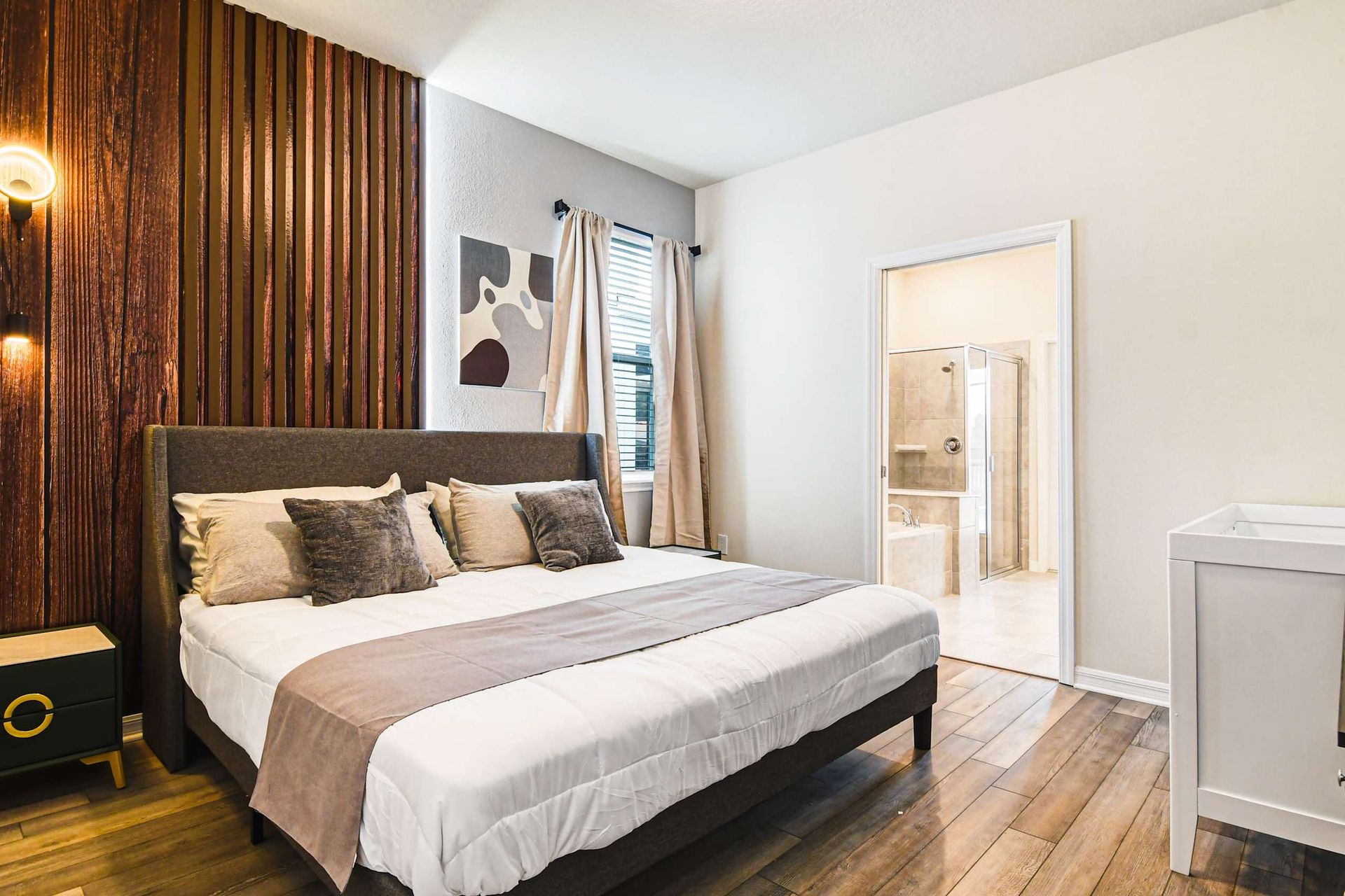 Serene master bedroom with wood accent wall, king bed, and en-suite bathroom.