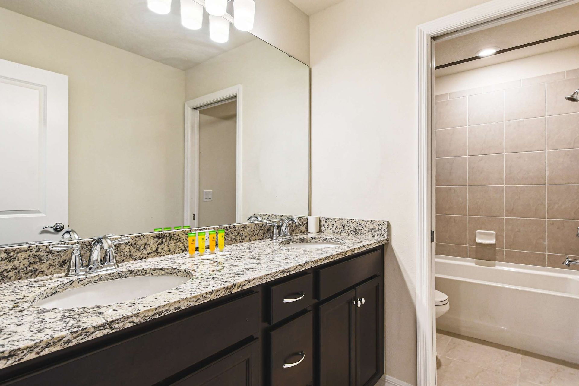 Modern bathroom with granite double vanity and tub-shower combo—comfort for all!