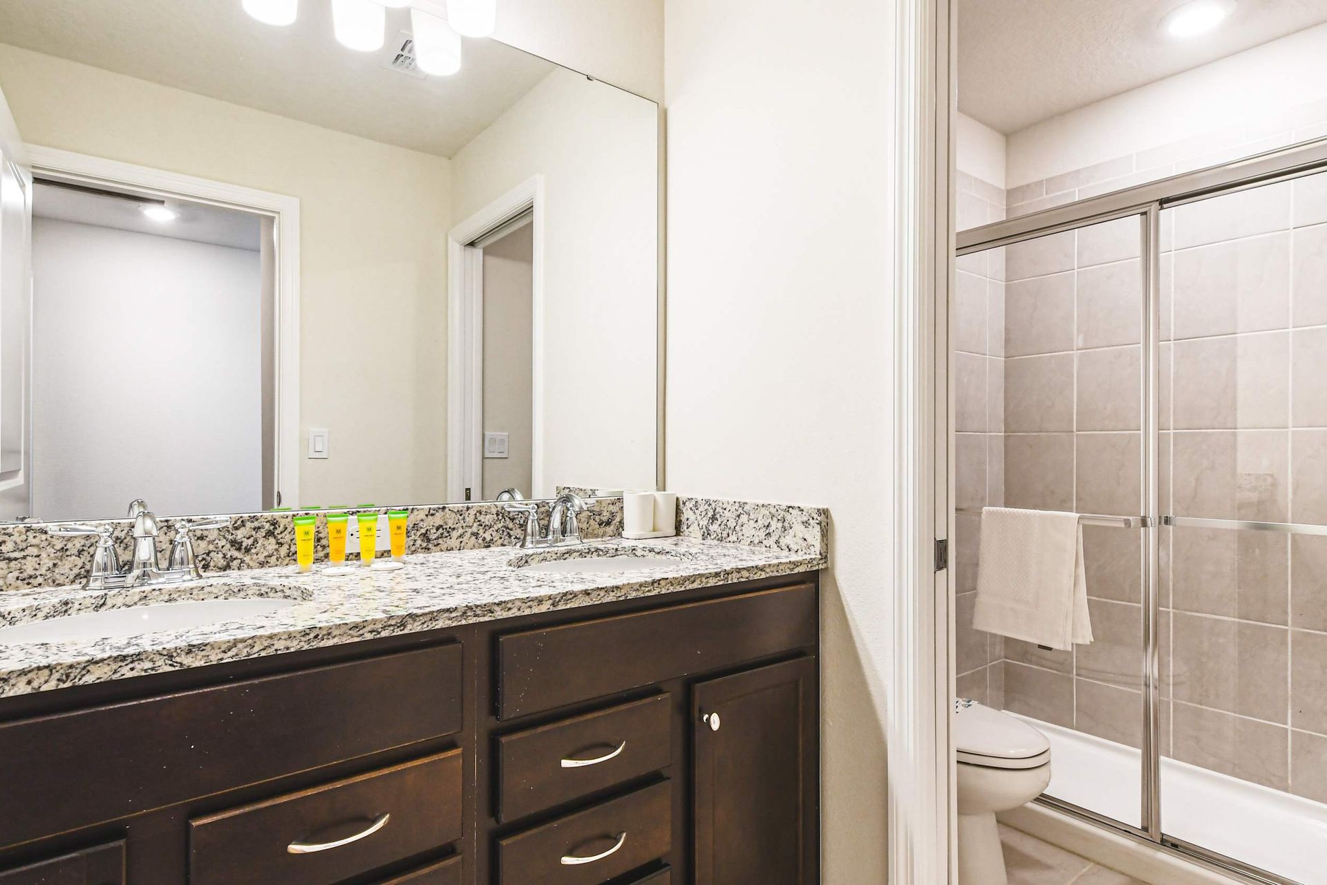 Stylish bathroom with granite double sinks and a sleek glass-enclosed shower!