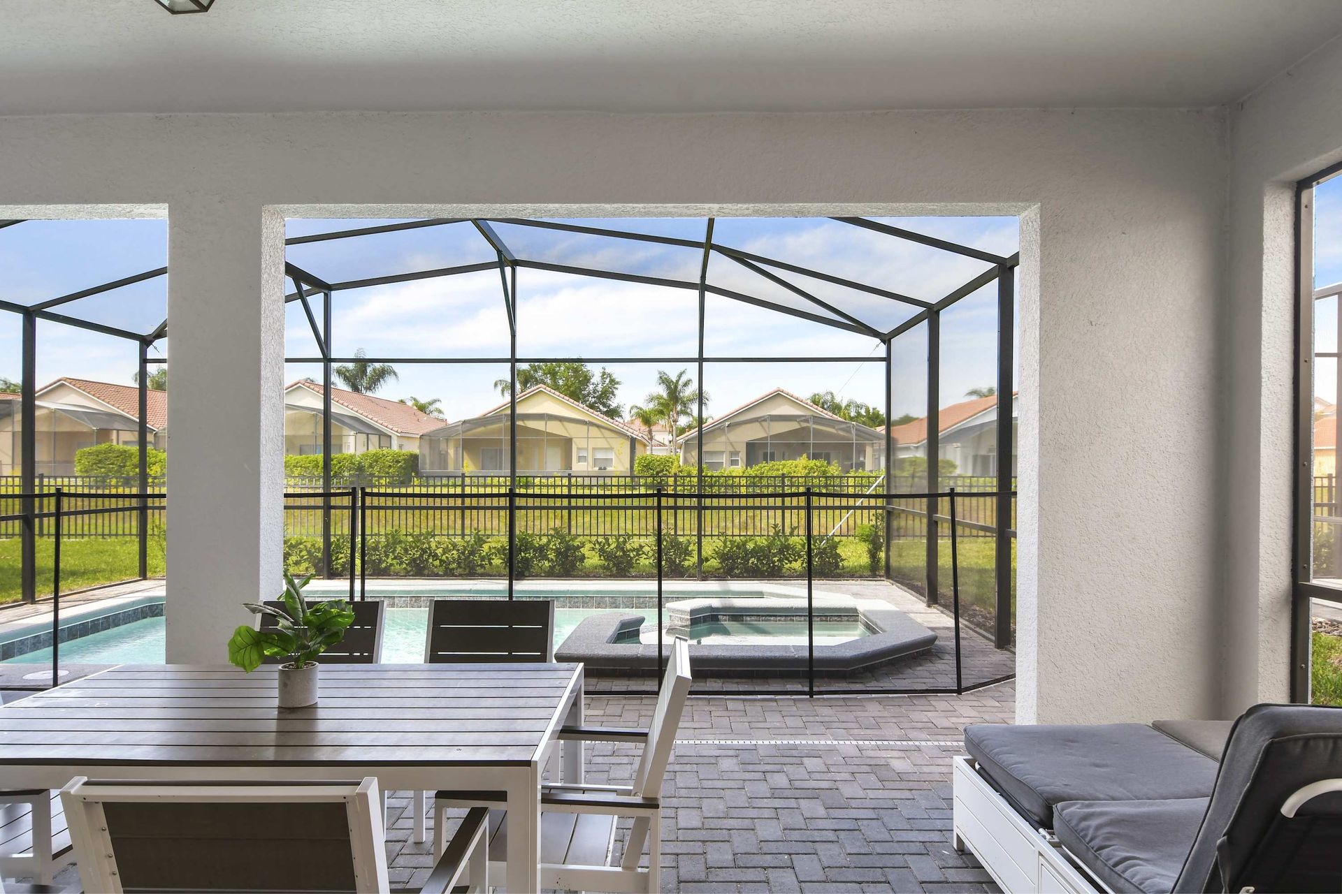 Covered patio with dining area, lounge seating, and screened pool with spa view.