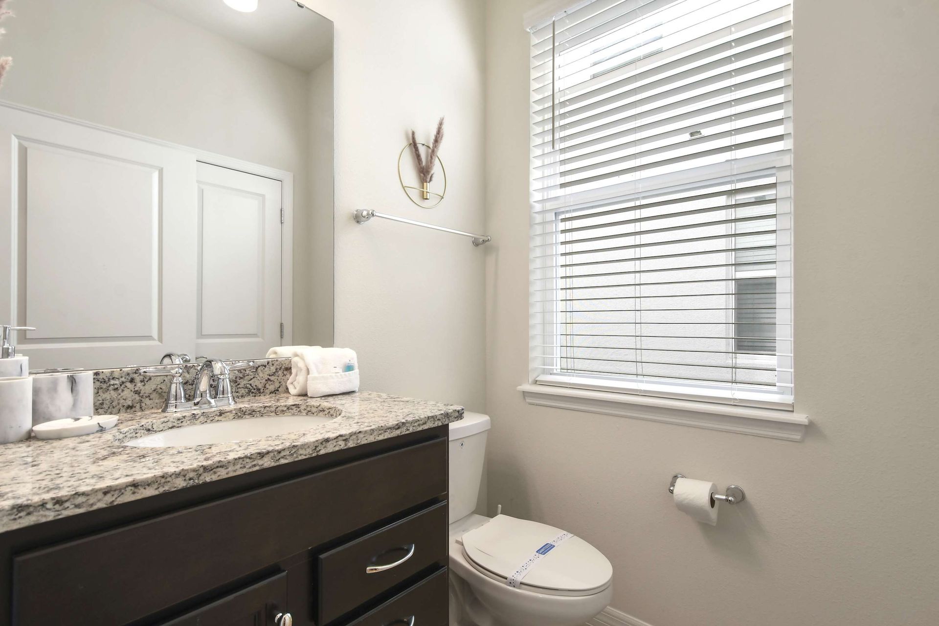 Bright and modern bathroom with granite vanity, natural light, and sleek finishes.