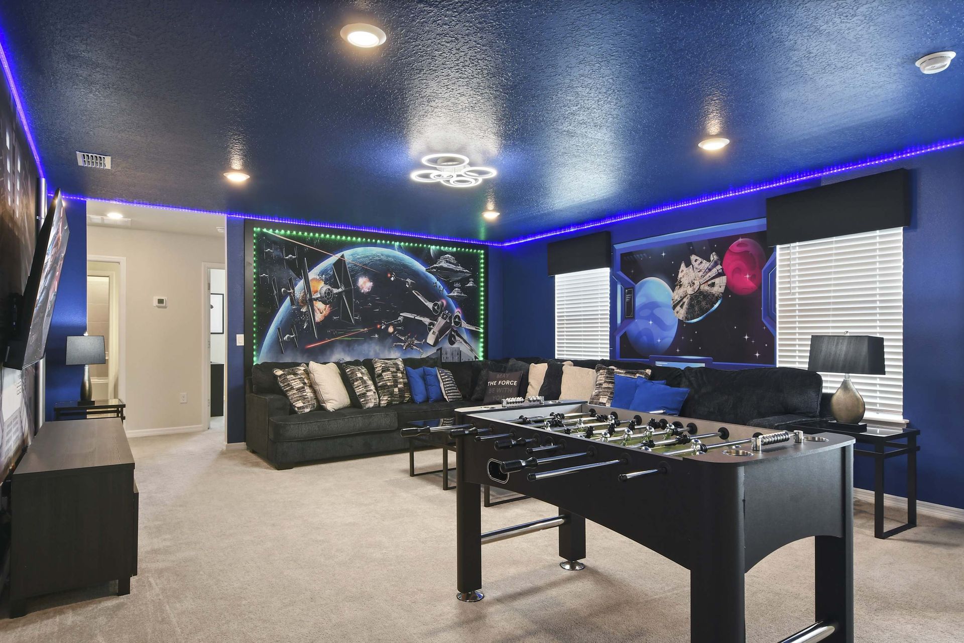 Immersive galaxy-themed game room with foosball, LED lights, and huge sofa setup.