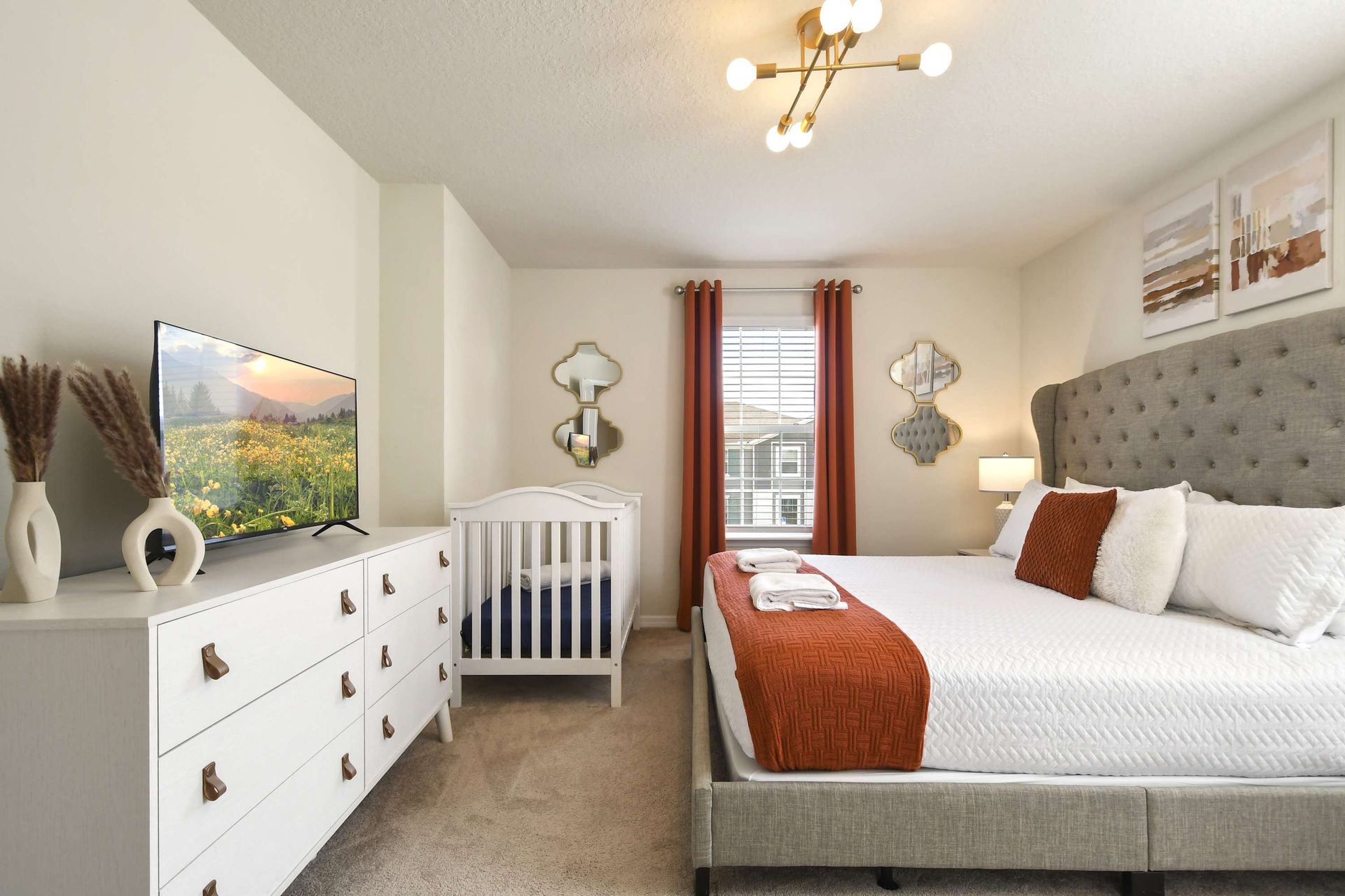 Serene bedroom with king bed, TV, crib, and soft neutral tones throughout.